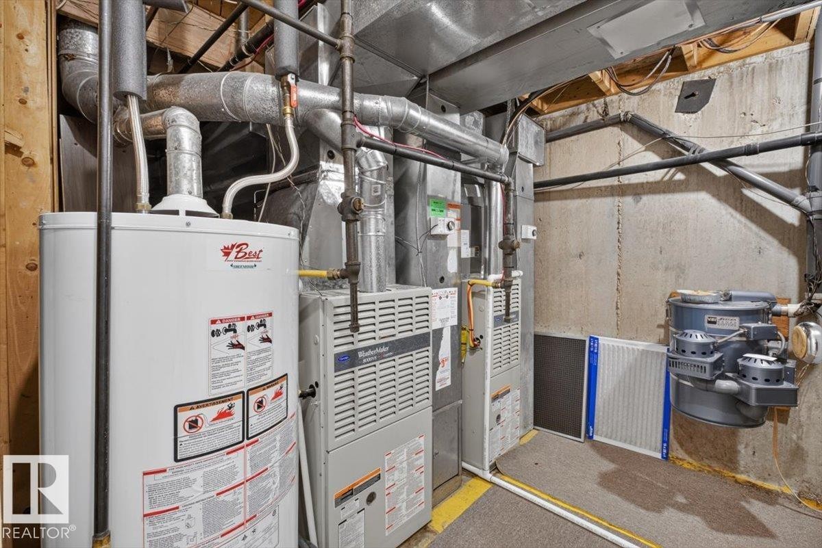 Utility area featuring a water heater, two furnaces, exposed ductwork, and plumbing - 4027 74 Street Nw, Edmonton, AB - Indoor Photo Showing Basement