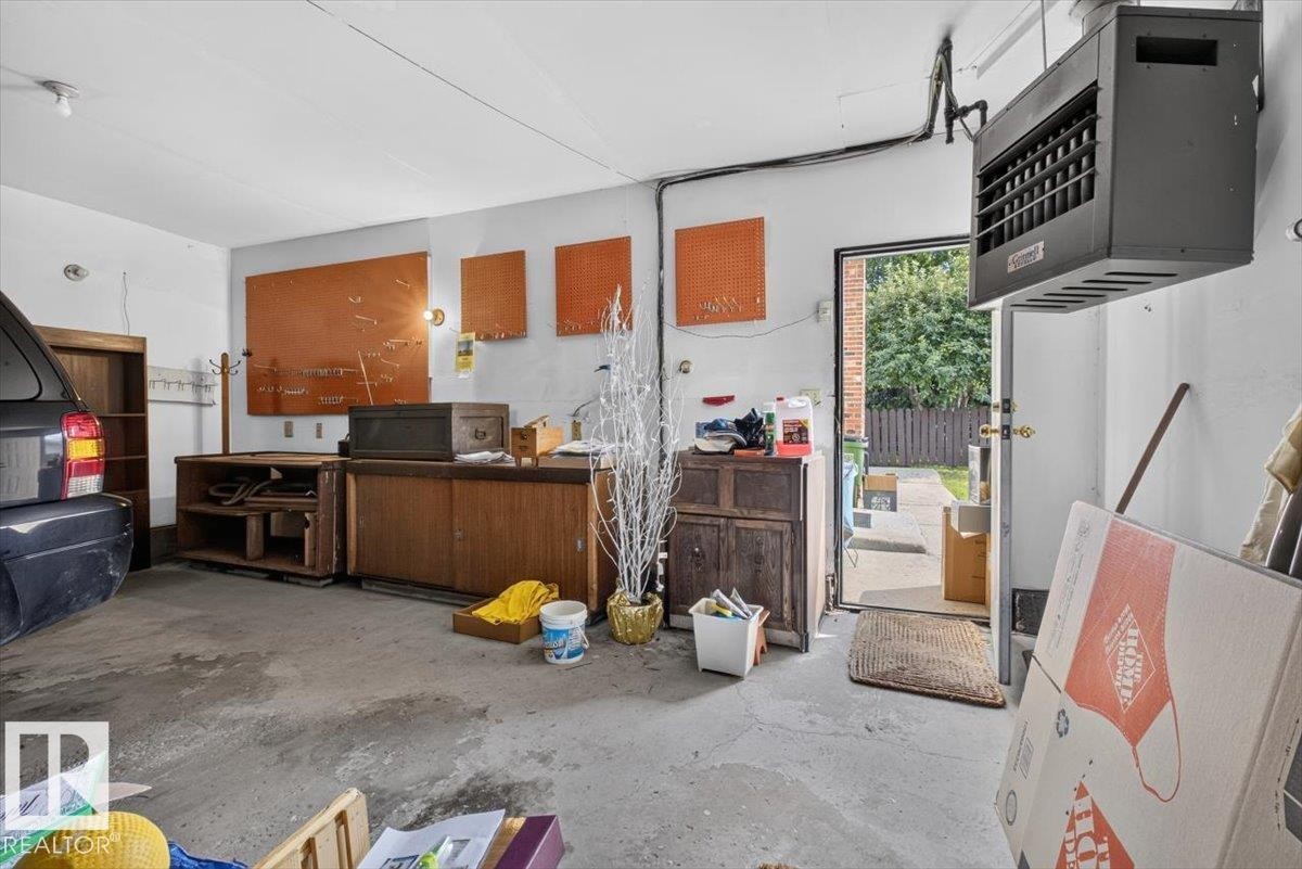 Concrete floor garage with a wall-mounted heater, rear access door, and track lighting - 4027 74 Street Nw, Edmonton, AB - Indoor Photo Showing Garage