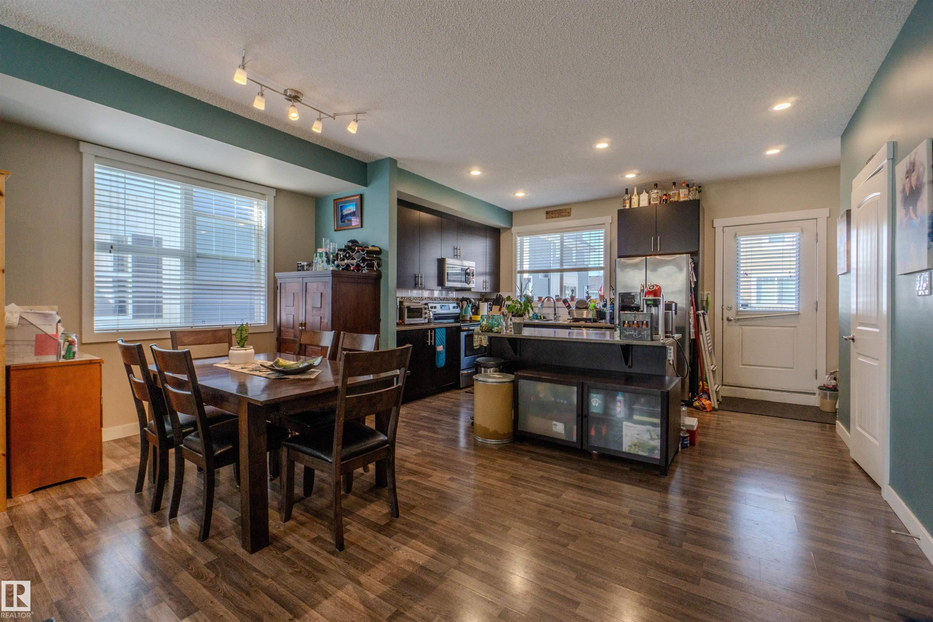 Open-concept living space featuring wood-finish flooring, recessed lighting, and a track light fixture - #75 8315 180 Av Nw, Edmonton, AB
