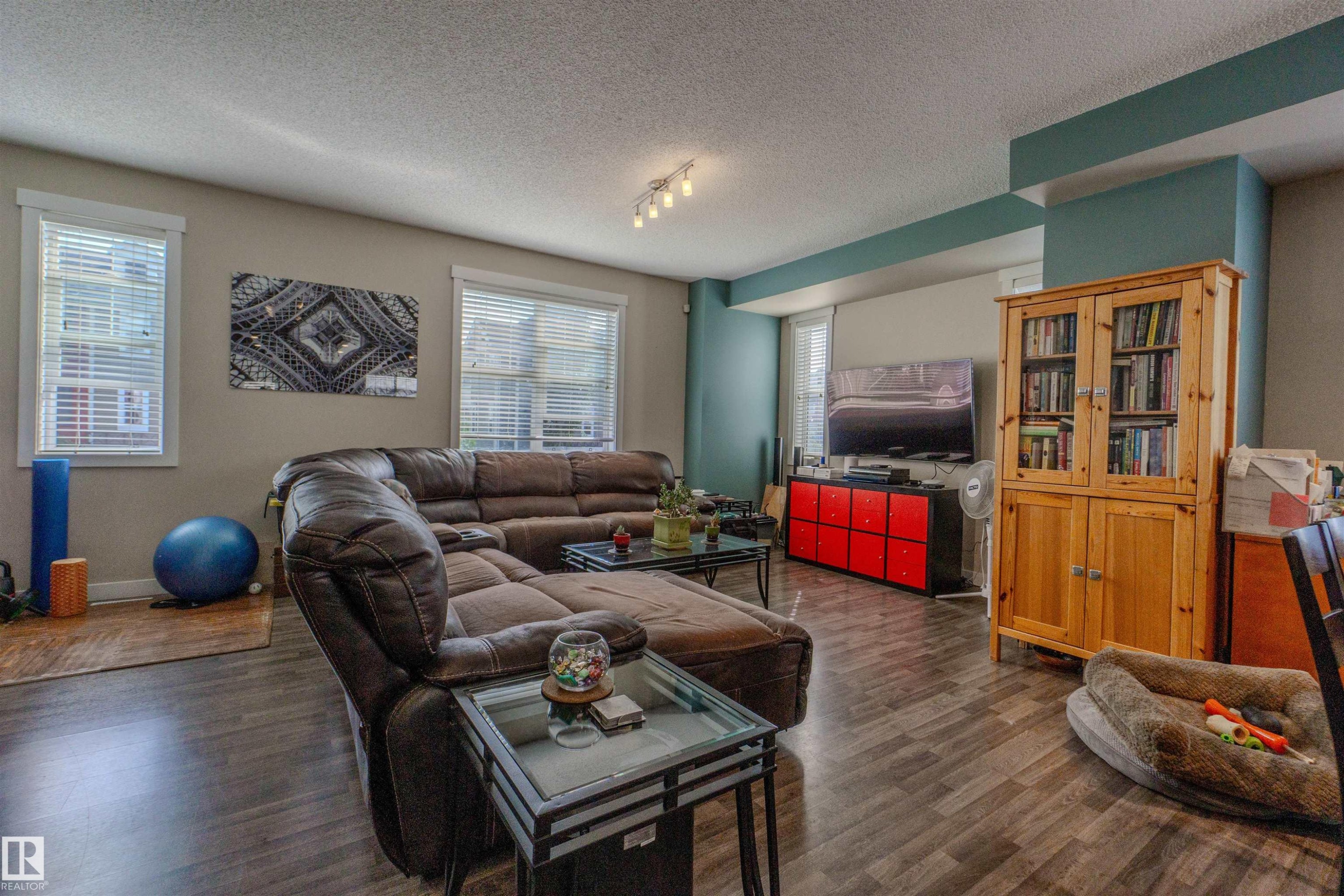Spacious living area featuring wood-finish flooring, multiple windows, and recessed lighting - #75 8315 180 Av Nw, Edmonton, AB