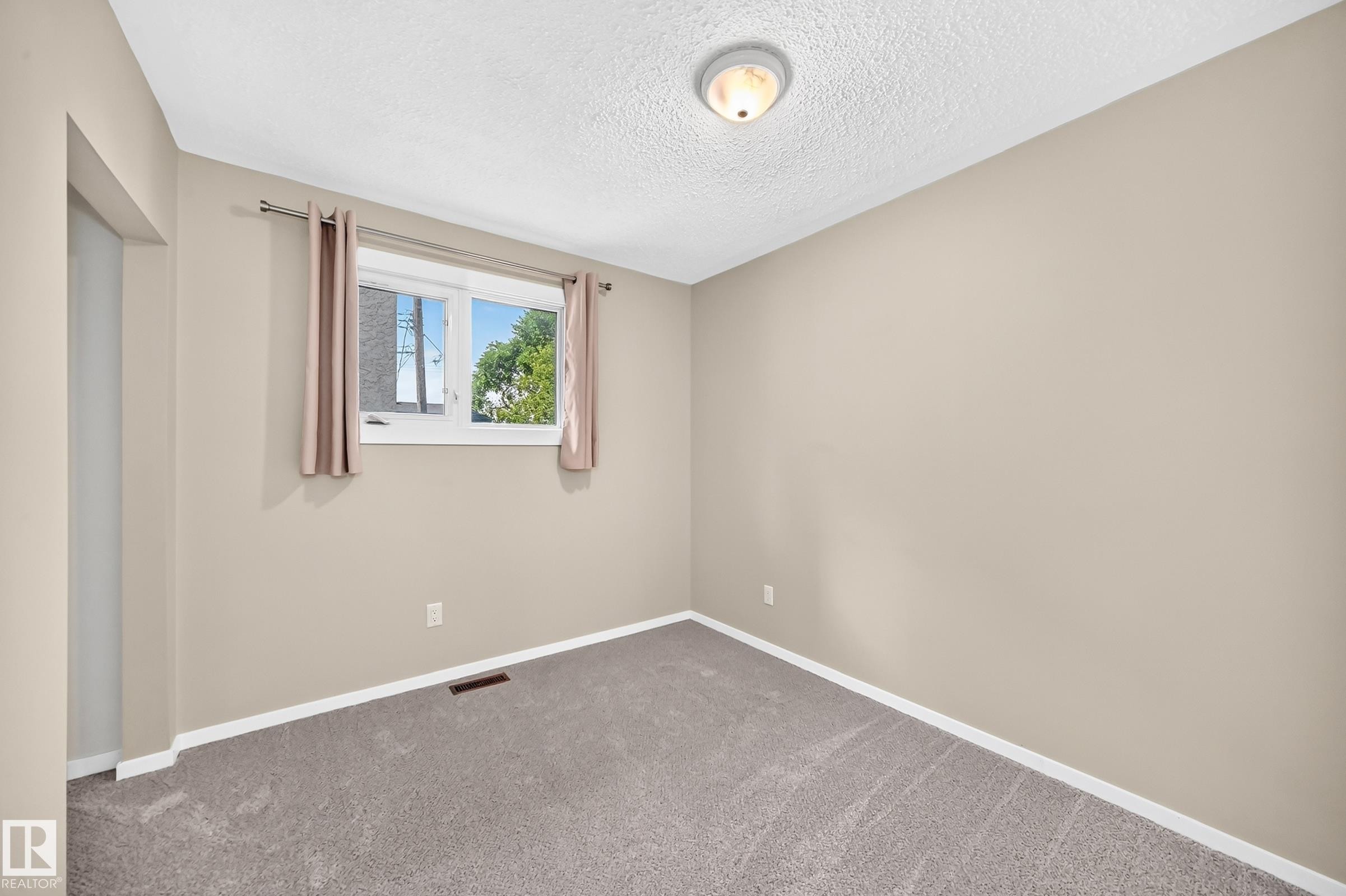 Neutral-toned walls with contrasting white trim, grey carpeting, and a single window - 12721 117 Street Nw, Edmonton, AB