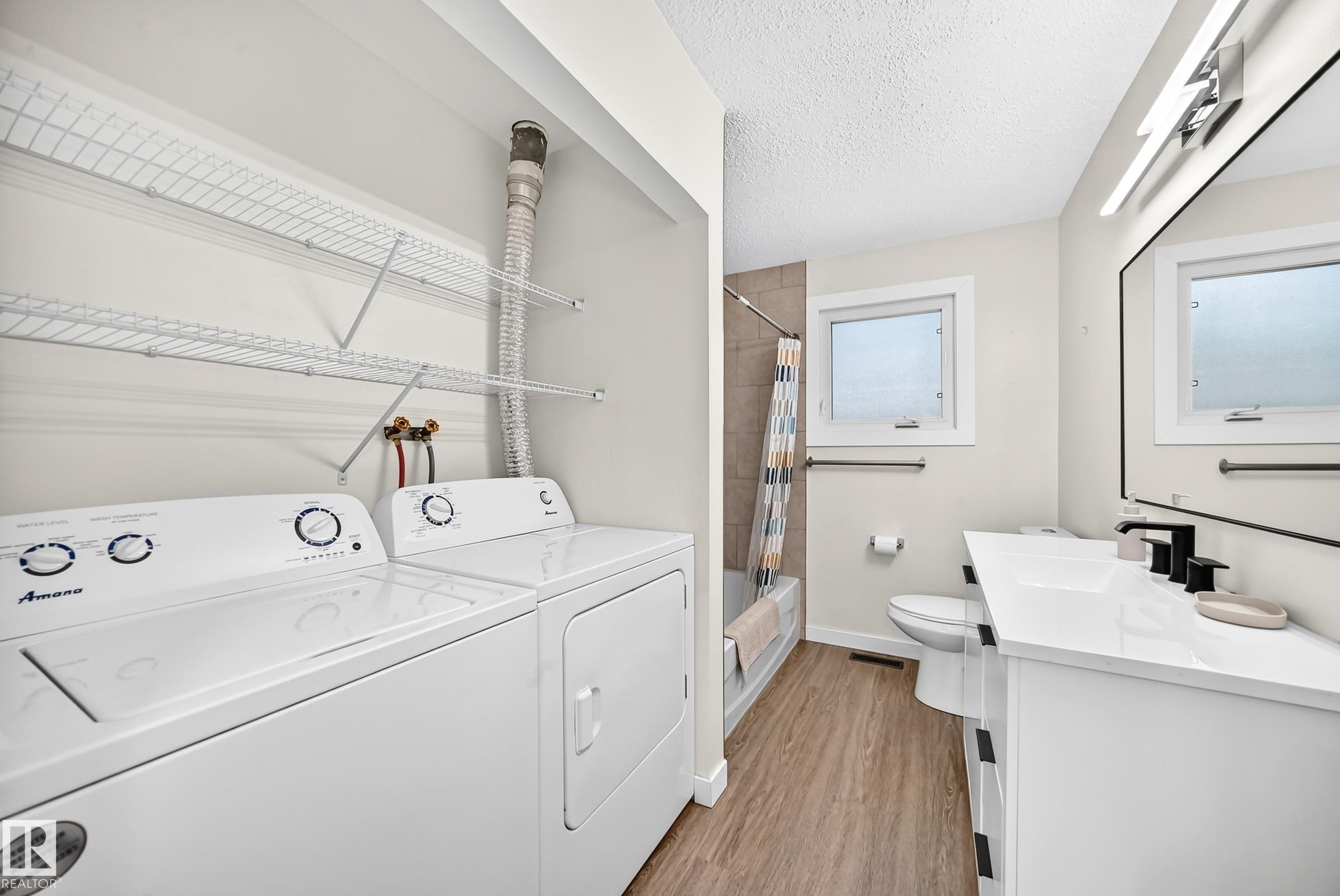 Bathroom featuring a white vanity with a rectangular sink, matte black faucet, and a wall-mounted mirror - 12721 117 Street Nw, Edmonton, AB
