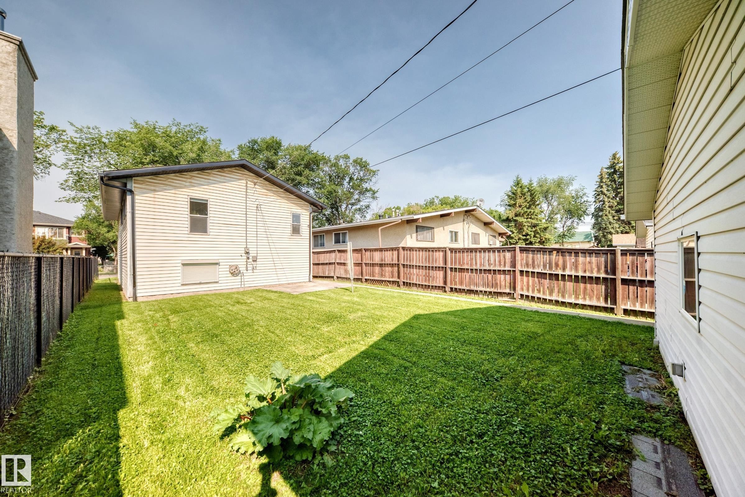 Expansive fenced backyard featuring a manicured lawn and a privacy fence - 12721 117 Street Nw, Edmonton, AB