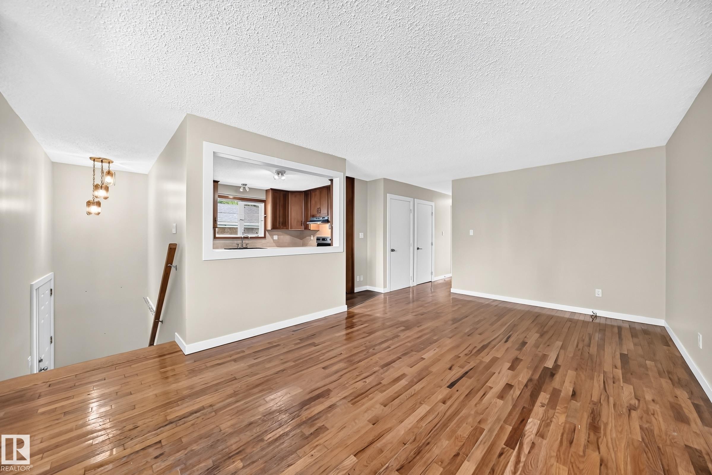 Hardwood flooring, neutral wall tones, interior pass-through window, built-in lighting fixture, and white trim throughout - 12721 117 Street Nw, Edmonton, AB