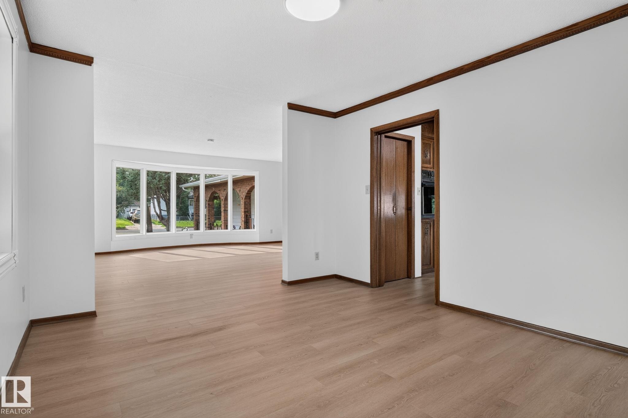 Bright interior featuring wood-finish flooring, white walls, and dark wood trim - 12121 42 Street Nw, Edmonton, AB - Indoor Photo Showing Other Room