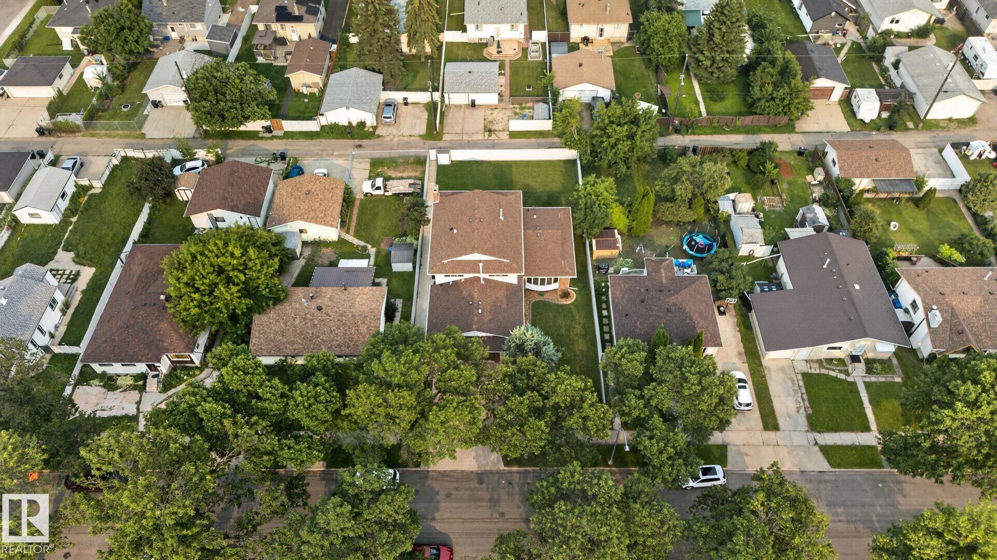 Expansive aerial view of a residential neighborhood featuring multiple single-family homes with brown shingled roofs and varied landscaping - 12121 42 Street Nw, Edmonton, AB - Outdoor With View