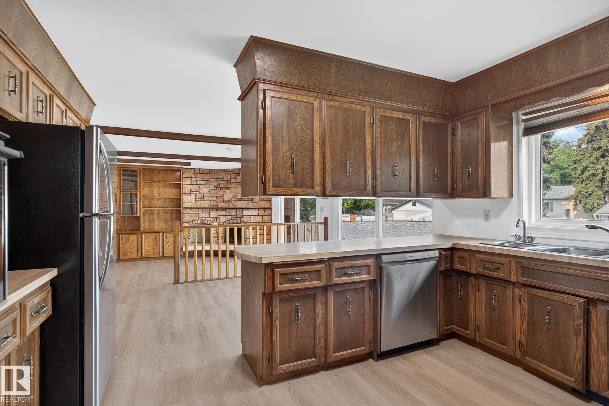 Kitchen featuring wood cabinetry, light-toned countertops, and light wood-finish flooring - 12121 42 Street Nw, Edmonton, AB - Indoor Photo Showing Kitchen