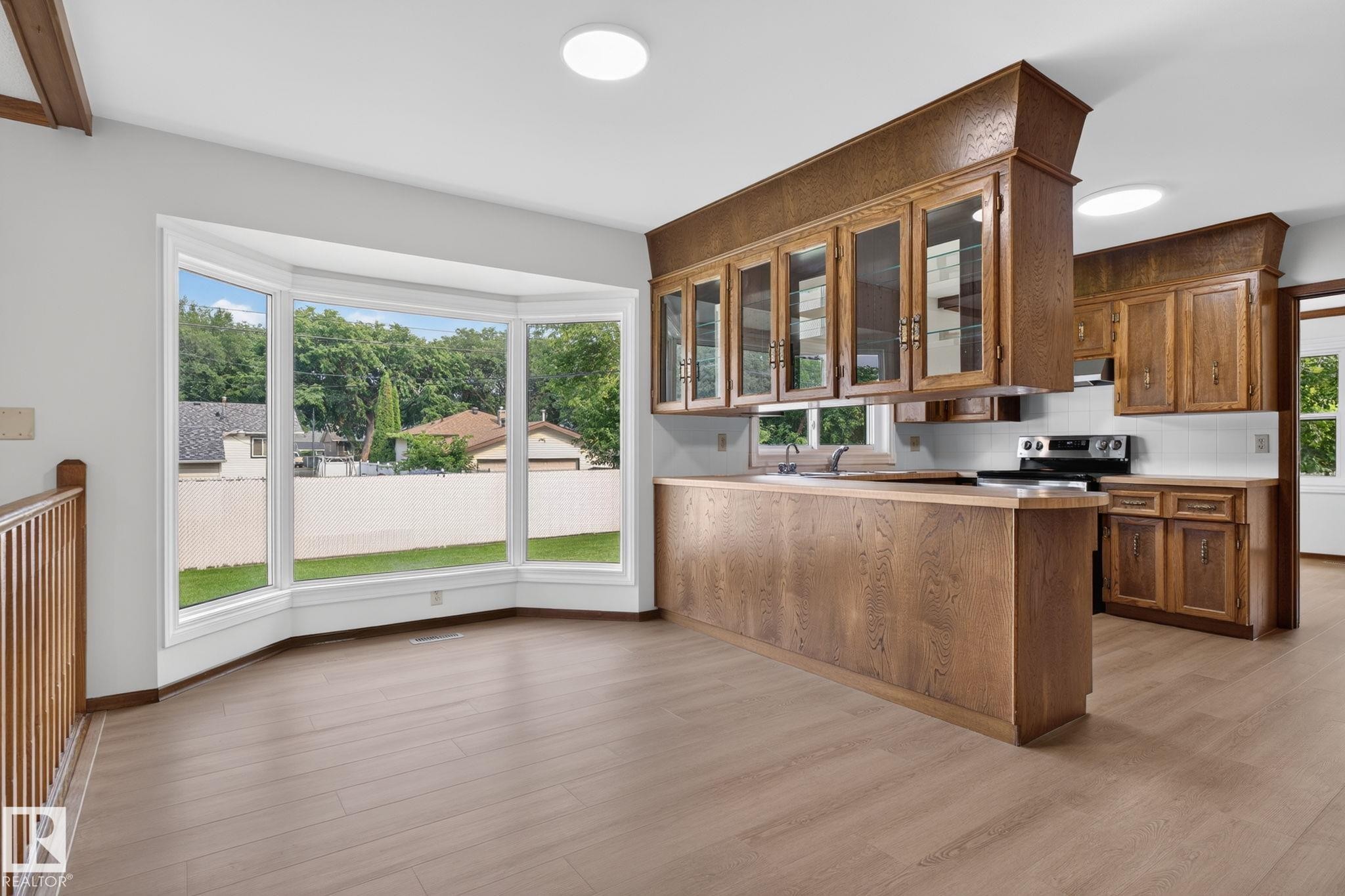 Expansive bay window featuring white trim and a view of exterior landscaping - 12121 42 Street Nw, Edmonton, AB - Indoor Photo Showing Kitchen