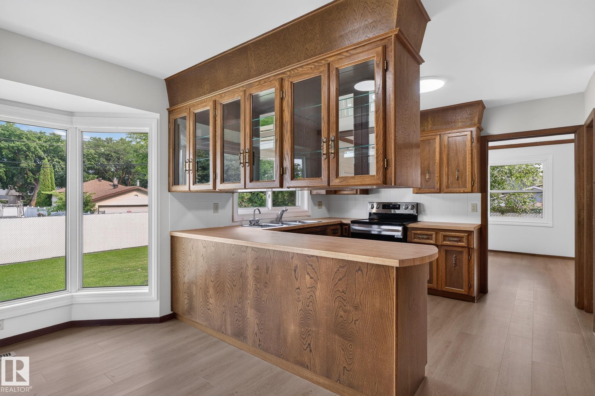 Kitchen featuring wood-finish cabinetry, a breakfast bar, and wood-finish flooring - 12121 42 Street Nw, Edmonton, AB -