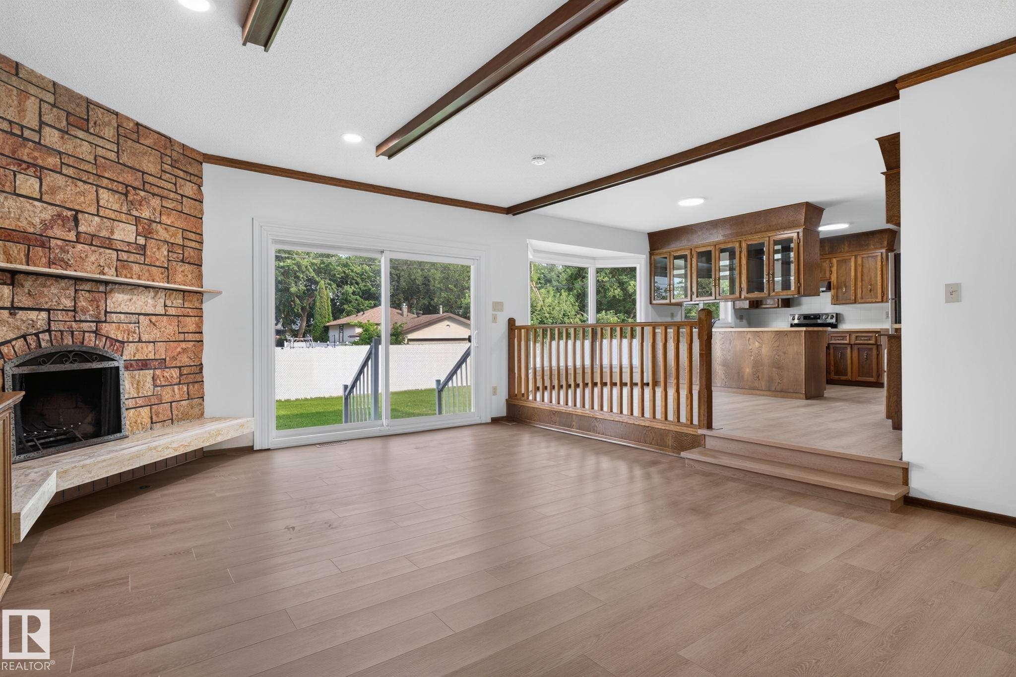 Spacious living area featuring a stone fireplace with hearth, wood-finish flooring, and recessed lighting - 12121 42 Street Nw, Edmonton, AB - Indoor With Fireplace
