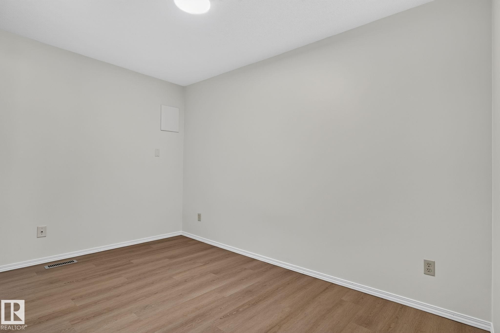 Room featuring light gray walls, wood-finish flooring, and white baseboards - 12121 42 Street Nw, Edmonton, AB - Indoor Photo Showing Other Room