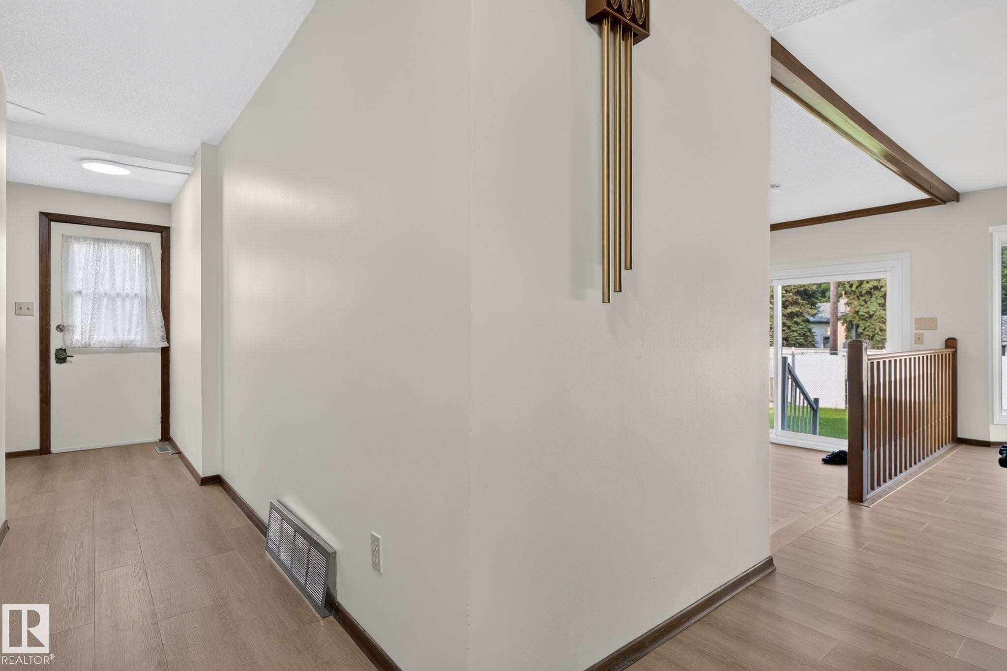Open-concept interior featuring wood-finish flooring, white walls, and dark wood trim - 12121 42 Street Nw, Edmonton, AB - Indoor Photo Showing Other Room
