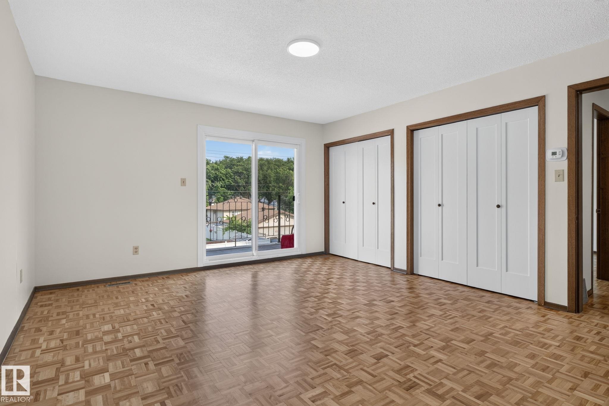 Hardwood parquet flooring with a sliding glass door providing exterior access - 12121 42 Street Nw, Edmonton, AB - Indoor Photo Showing Other Room
