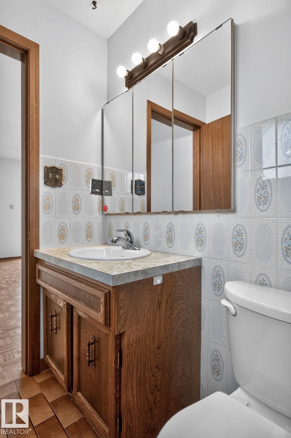 Bathroom vanity with wood-finish cabinetry, a drop-in sink, and a light-colored countertop - 12121 42 Street Nw, Edmonton, AB - Indoor Photo Showing Laundry Room