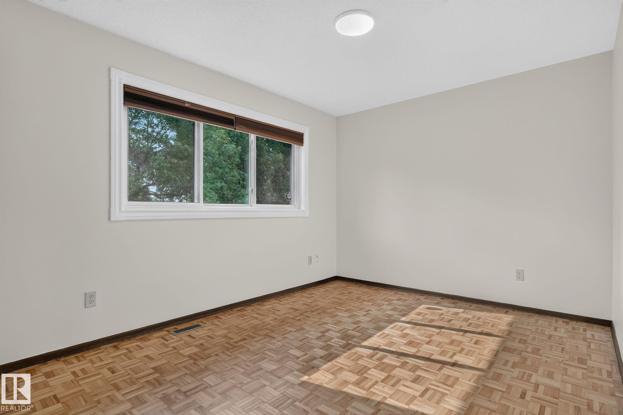 Room featuring light-toned walls and wood-finish parquet flooring - 12121 42 Street Nw, Edmonton, AB - Indoor Photo Showing Other Room