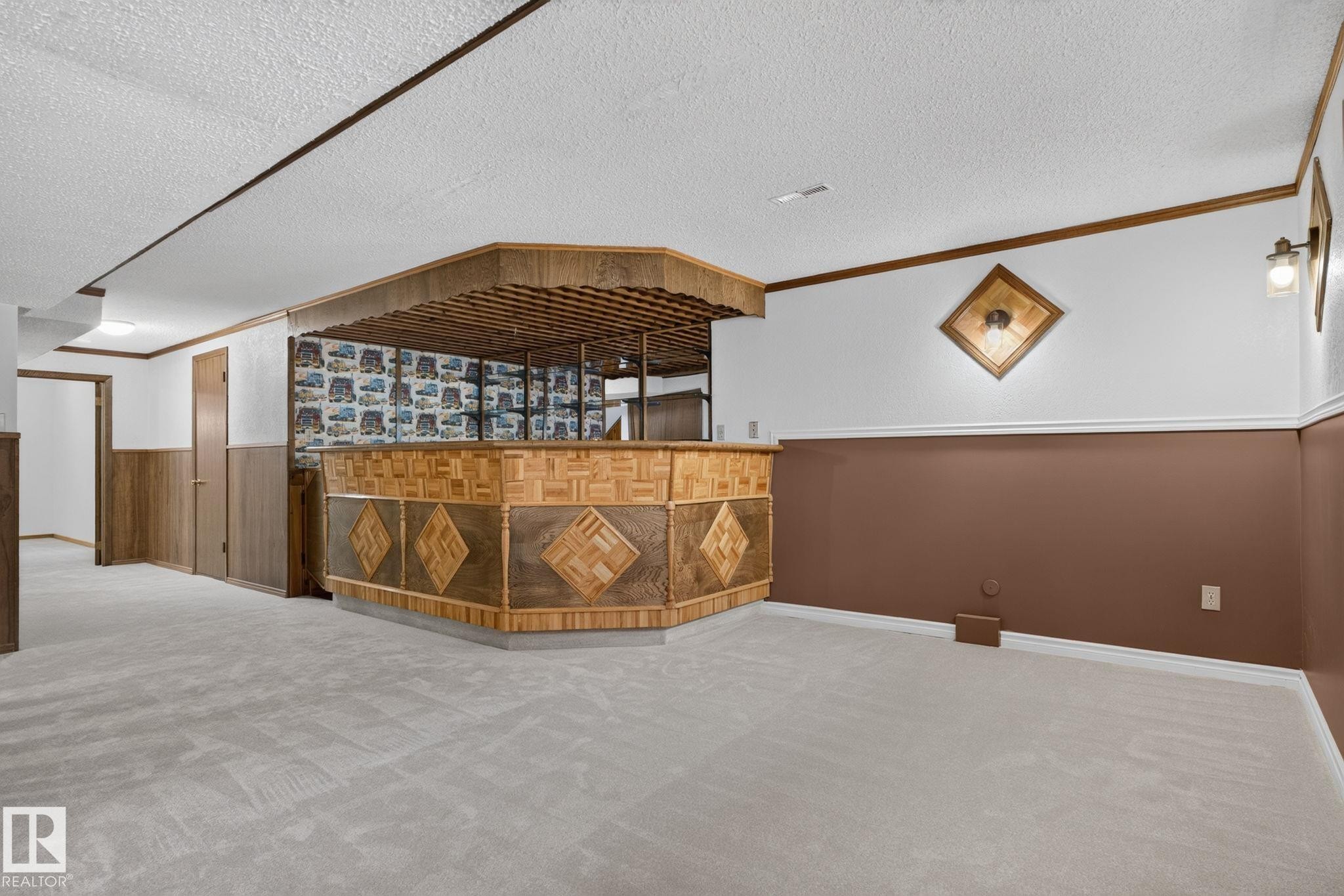 Spacious recreational area featuring a built-in bar with wood-finish paneling and patterned accents - 12121 42 Street Nw, Edmonton, AB - With Exterior