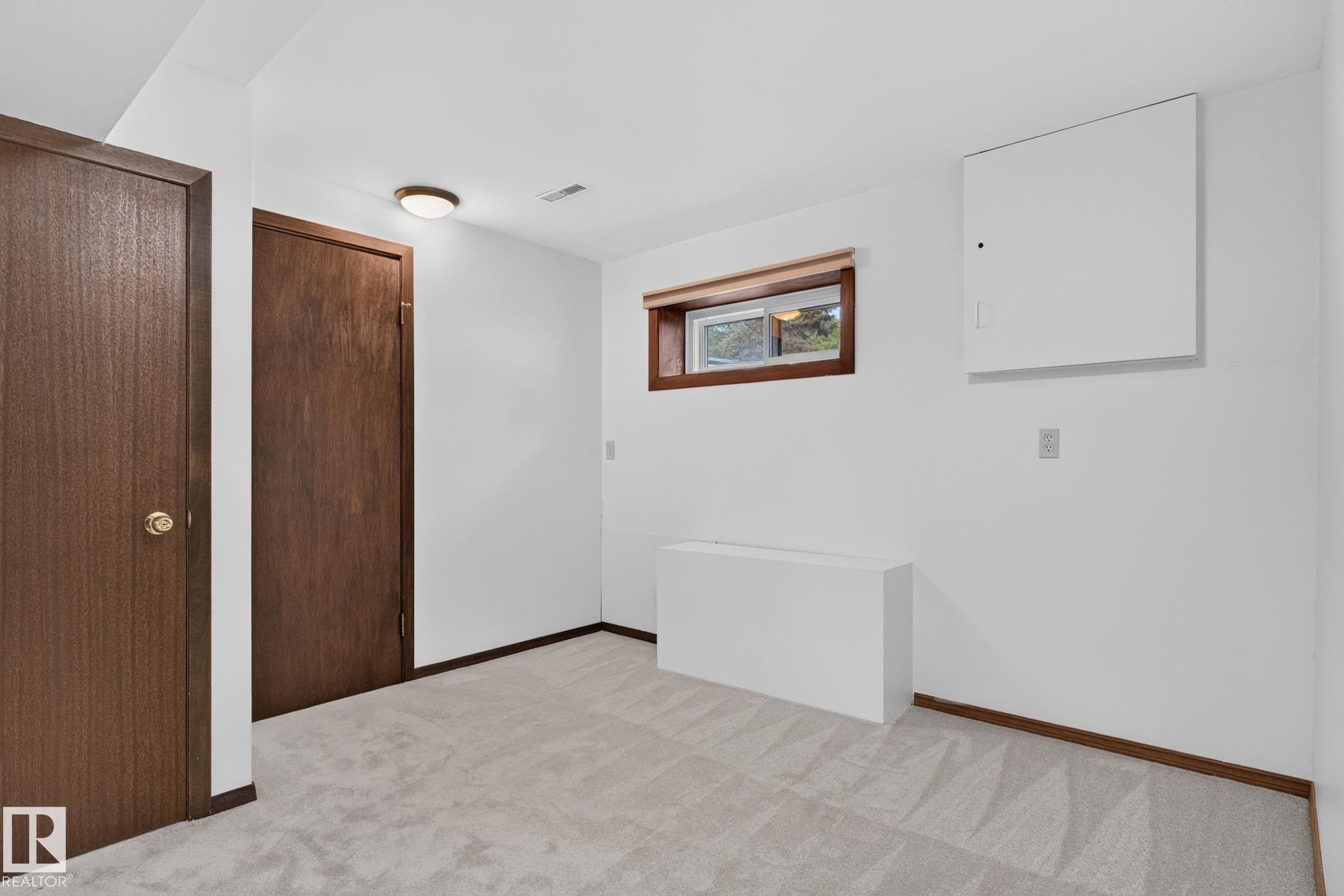 Carpeted room featuring white walls, a wood-framed window, two wood-paneled doors, and a flush-mount ceiling light - 12121 42 Street Nw, Edmonton, AB - Indoor Photo Showing Other Room