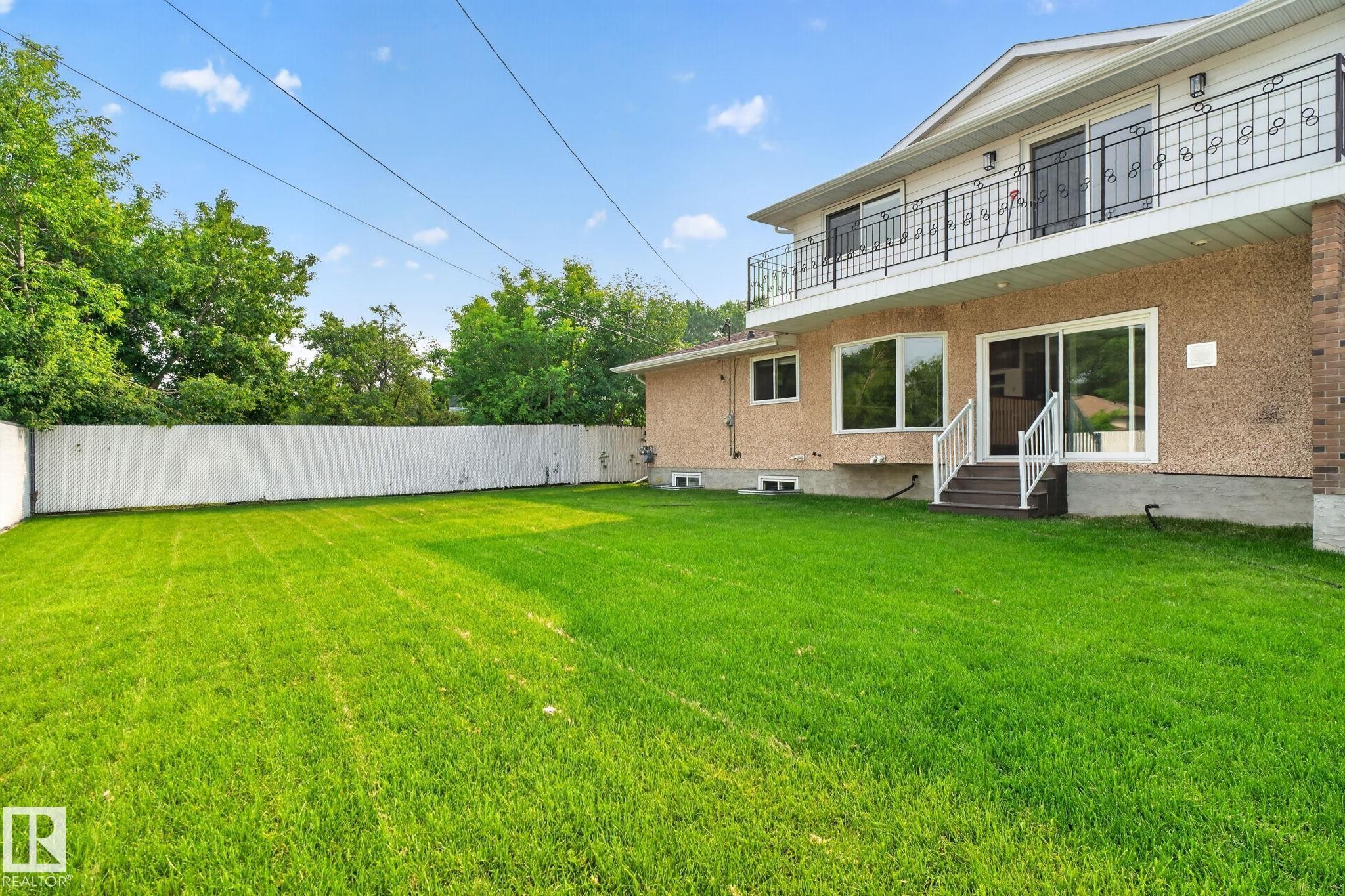 Expansive green lawn with a white privacy fence - 12121 42 Street Nw, Edmonton, AB - Outdoor With Balcony
