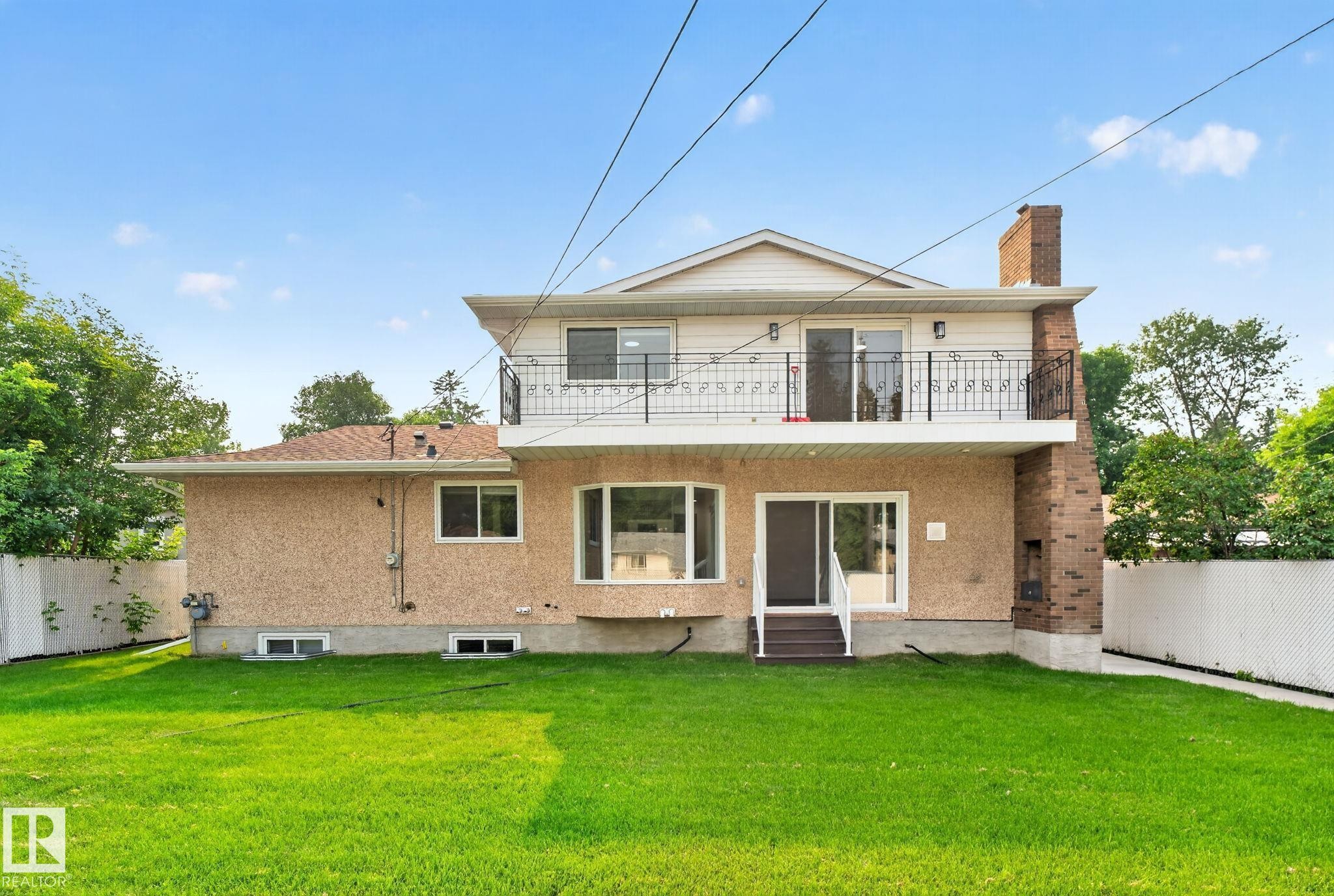 Expansive green lawn bordering a two-story residence with a stucco and siding exterior - 12121 42 Street Nw, Edmonton, AB - Outdoor With Balcony