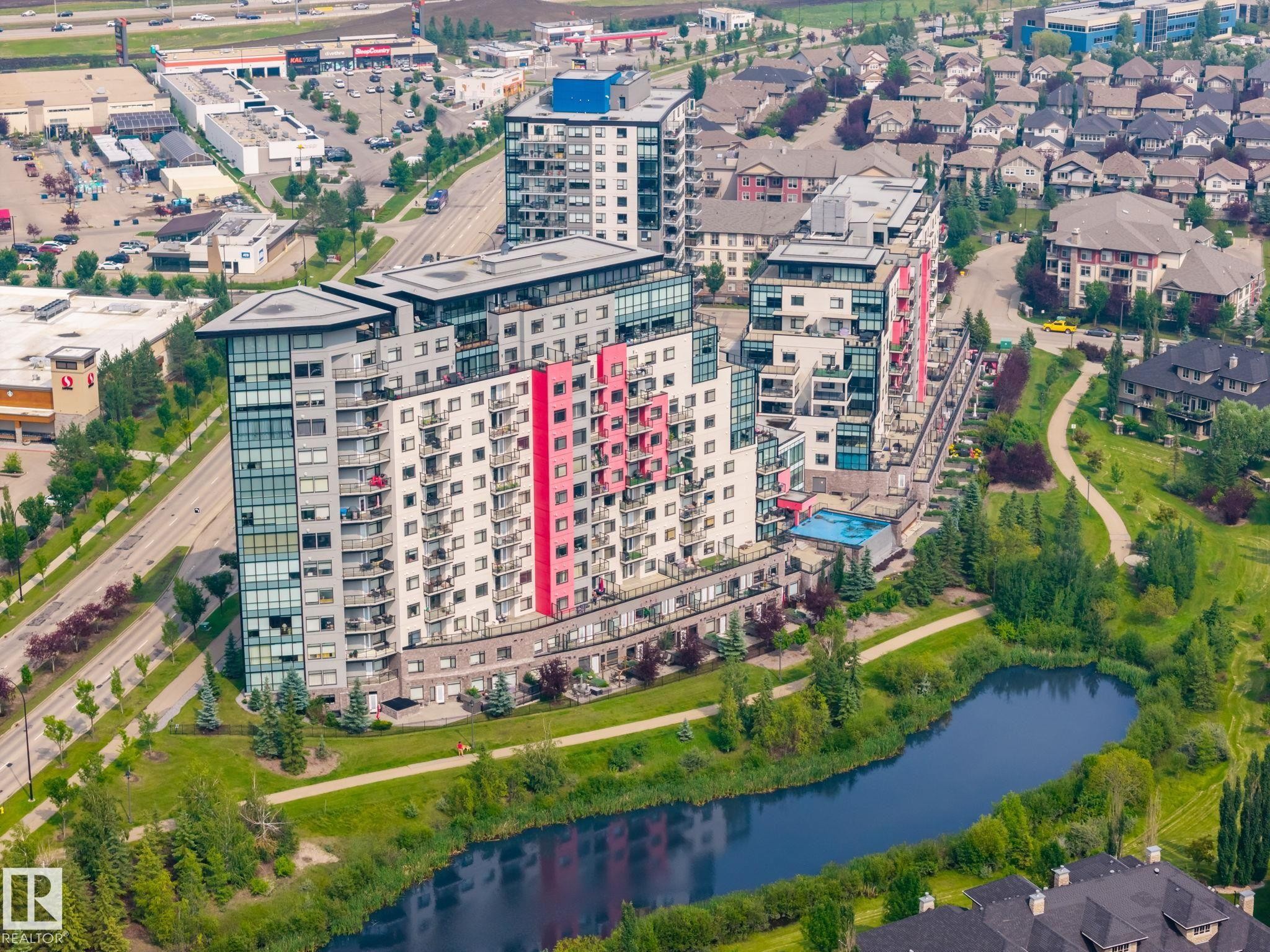 Modern high-rise residential building featuring multiple balconies, a rooftop amenity space, and an outdoor swimming pool - #324 5151 Windermere Bv Sw, Edmonton, AB - Outdoor With View