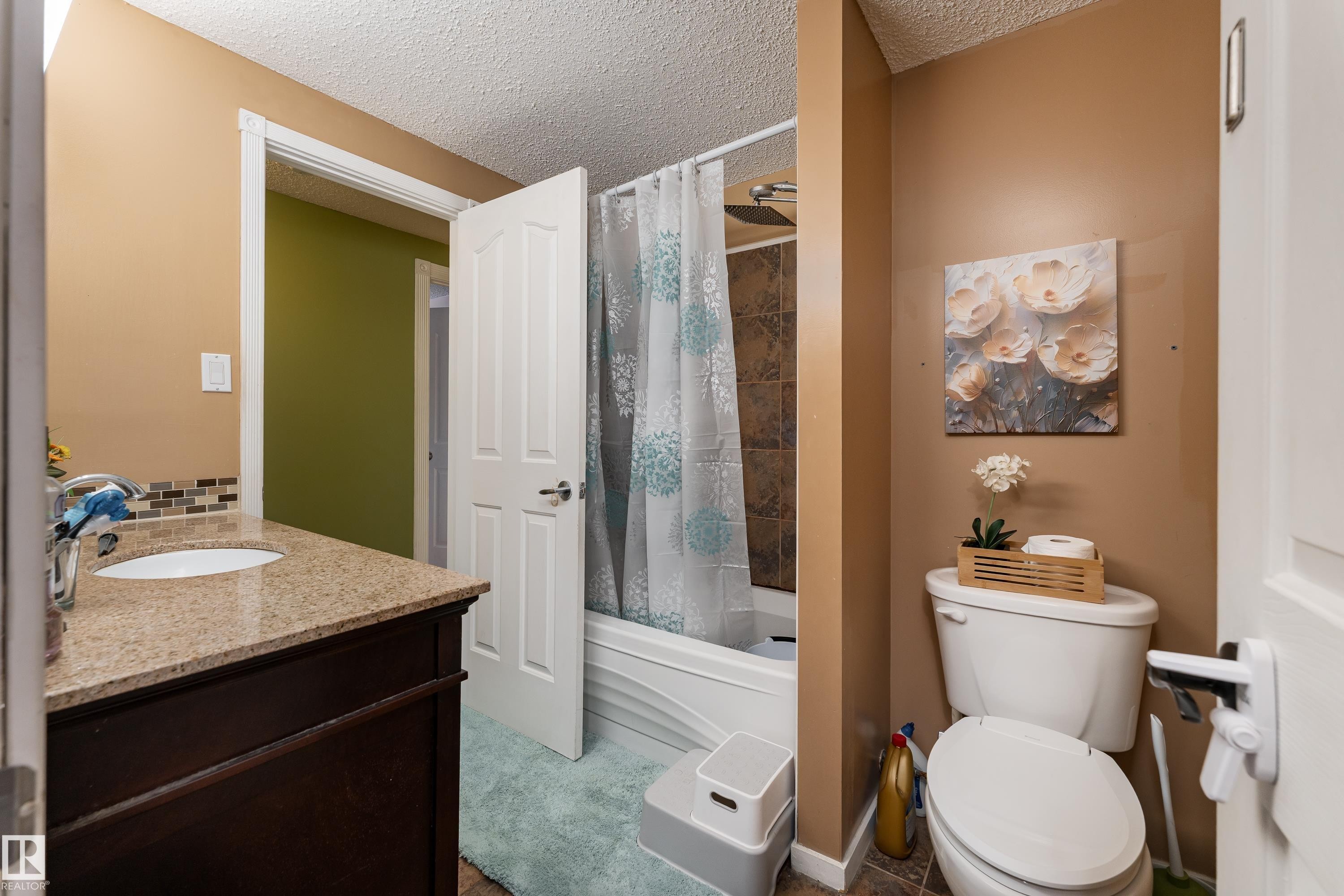 Vanity with a granite-style countertop, undermount sink, and tile backsplash - 17928 93 Ave Nw, Edmonton, AB