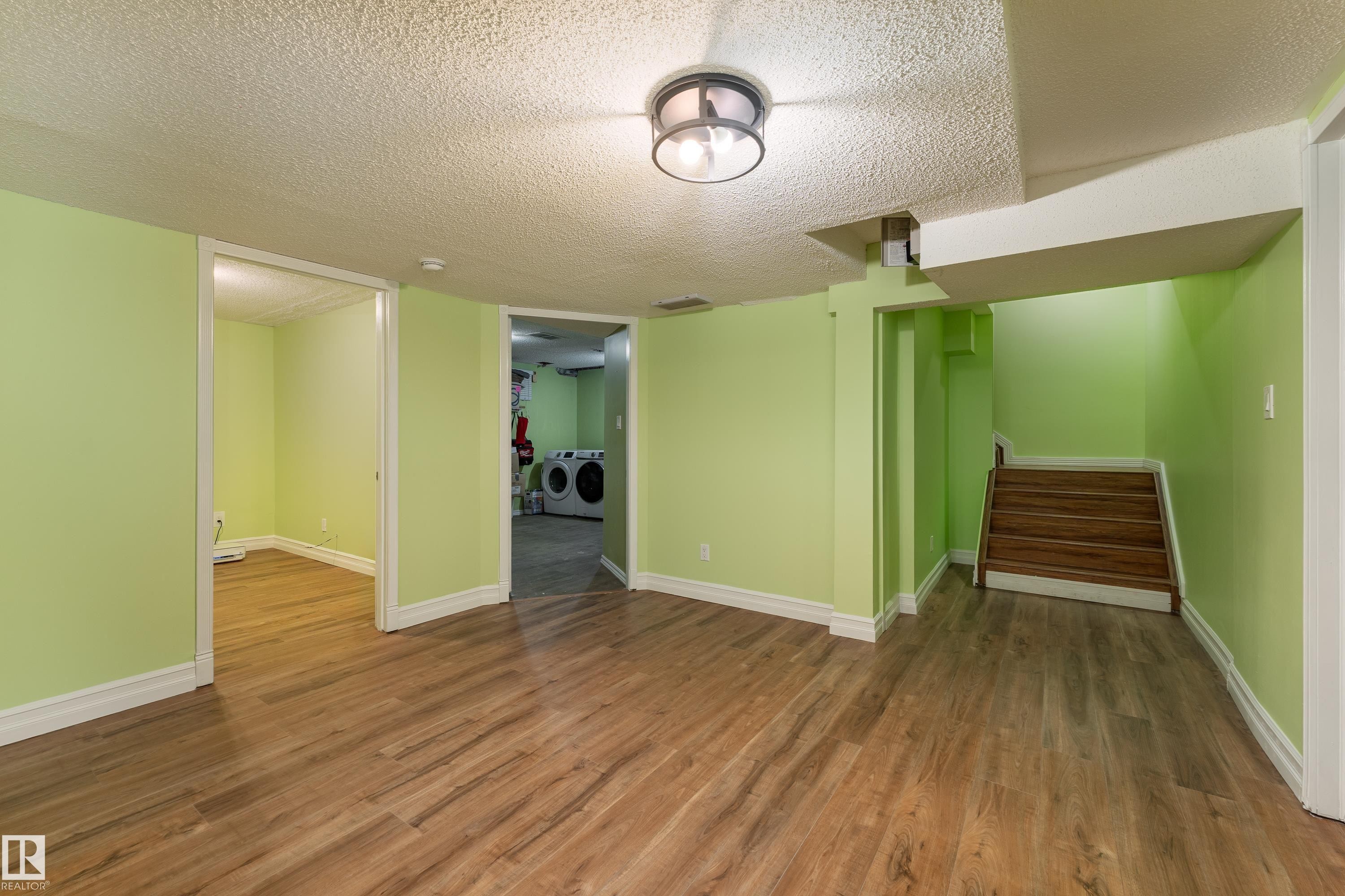 Wood-finish flooring throughout, featuring a surface-mounted light fixture, and a wood staircase - 17928 93 Ave Nw, Edmonton, AB
