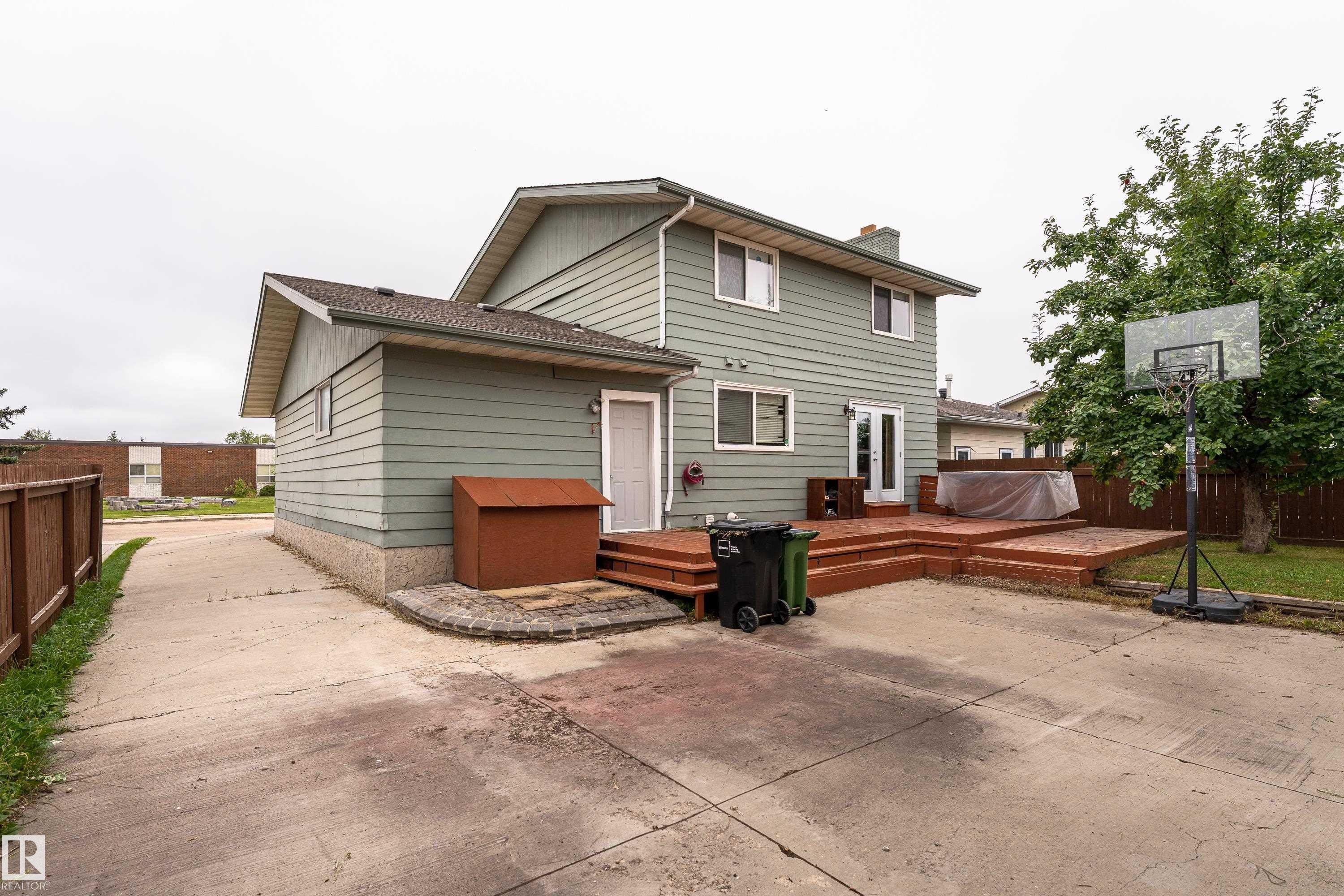 Multi-level wood deck with a built-in outdoor spa, complemented by a concrete patio and a fenced yard - 17928 93 Ave Nw, Edmonton, AB