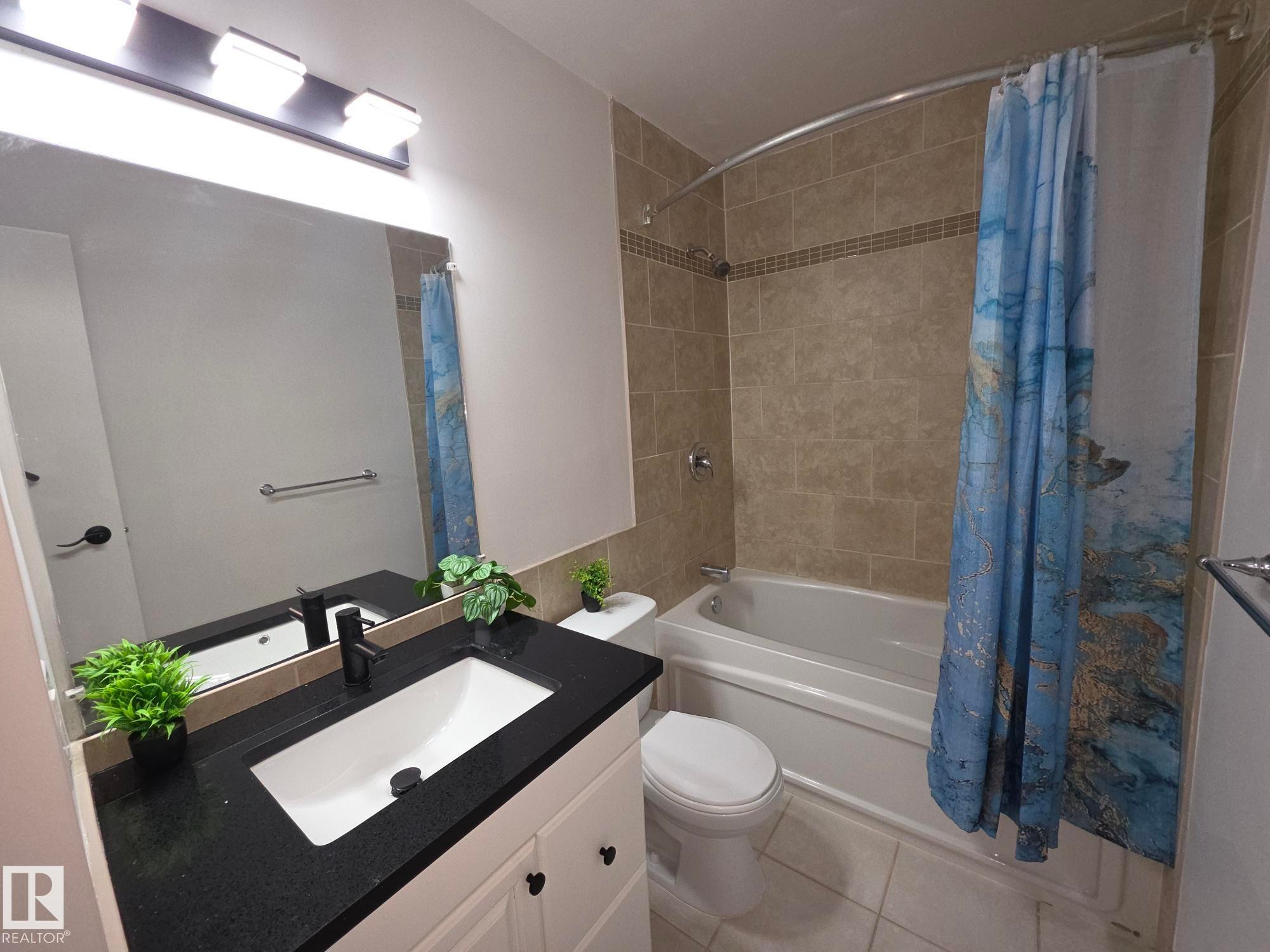 Bathroom featuring a vanity with a dark countertop, an undermount sink, and a large mirror - 140 Dickinsfield Court Nw, Edmonton, AB