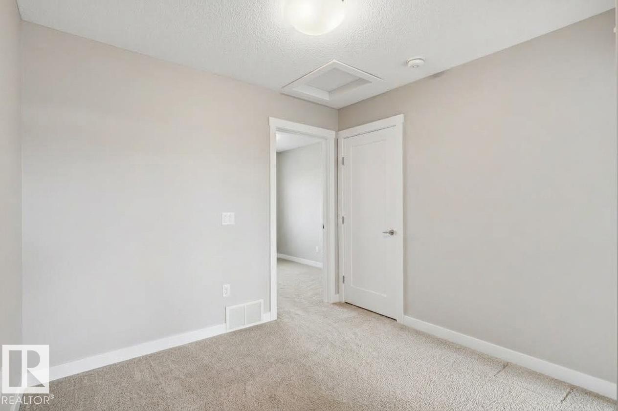Light gray wall paint, white trim, recessed lighting, white panel door, and light-colored carpet - #12 1391 Starling Dr Nw, Edmonton, AB