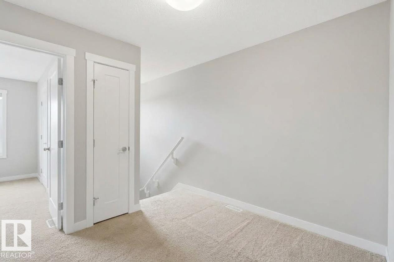 Light-colored carpeted flooring, white trim, and a white interior door with a silver-tone handle - #12 1391 Starling Dr Nw, Edmonton, AB