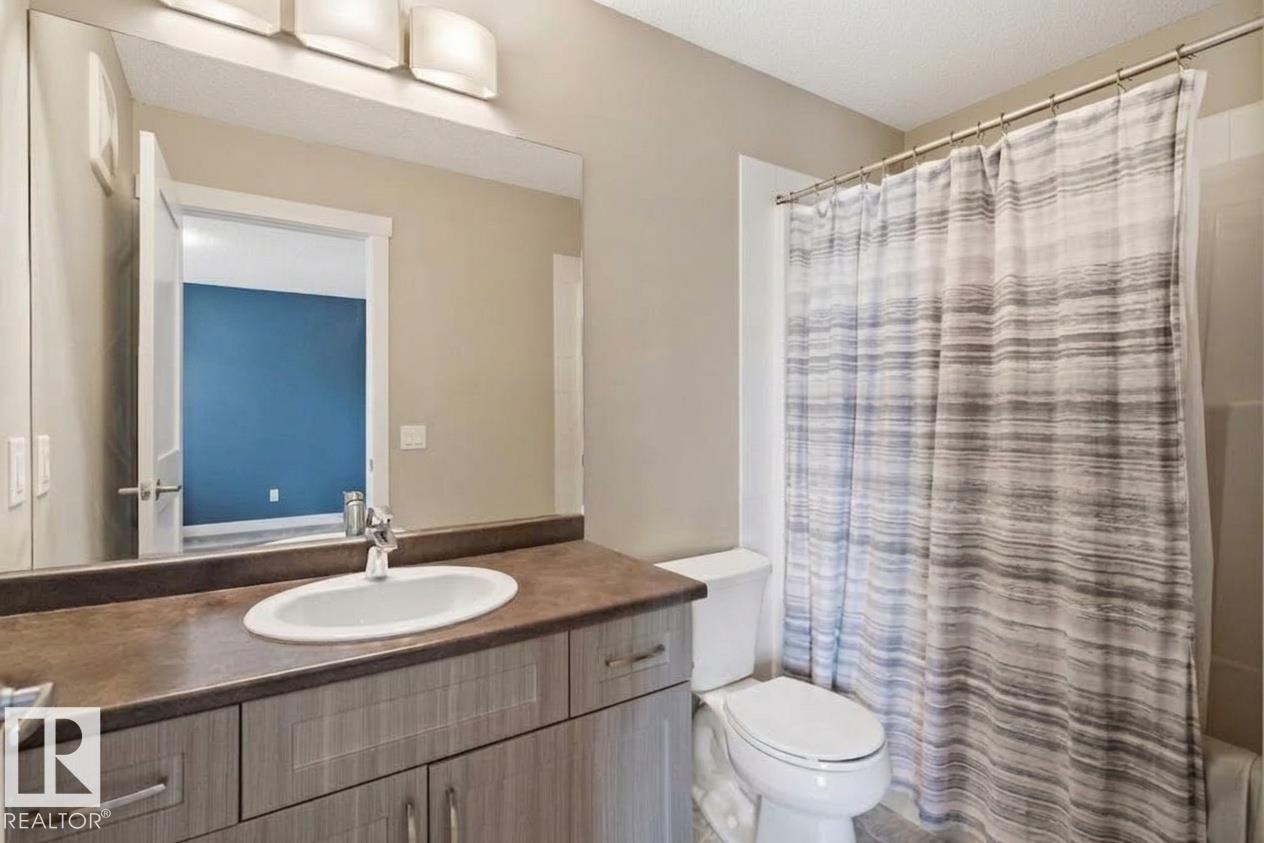 Vanity with an integrated sink, a large wall-mounted mirror, and overhead lighting - #12 1391 Starling Dr Nw, Edmonton, AB