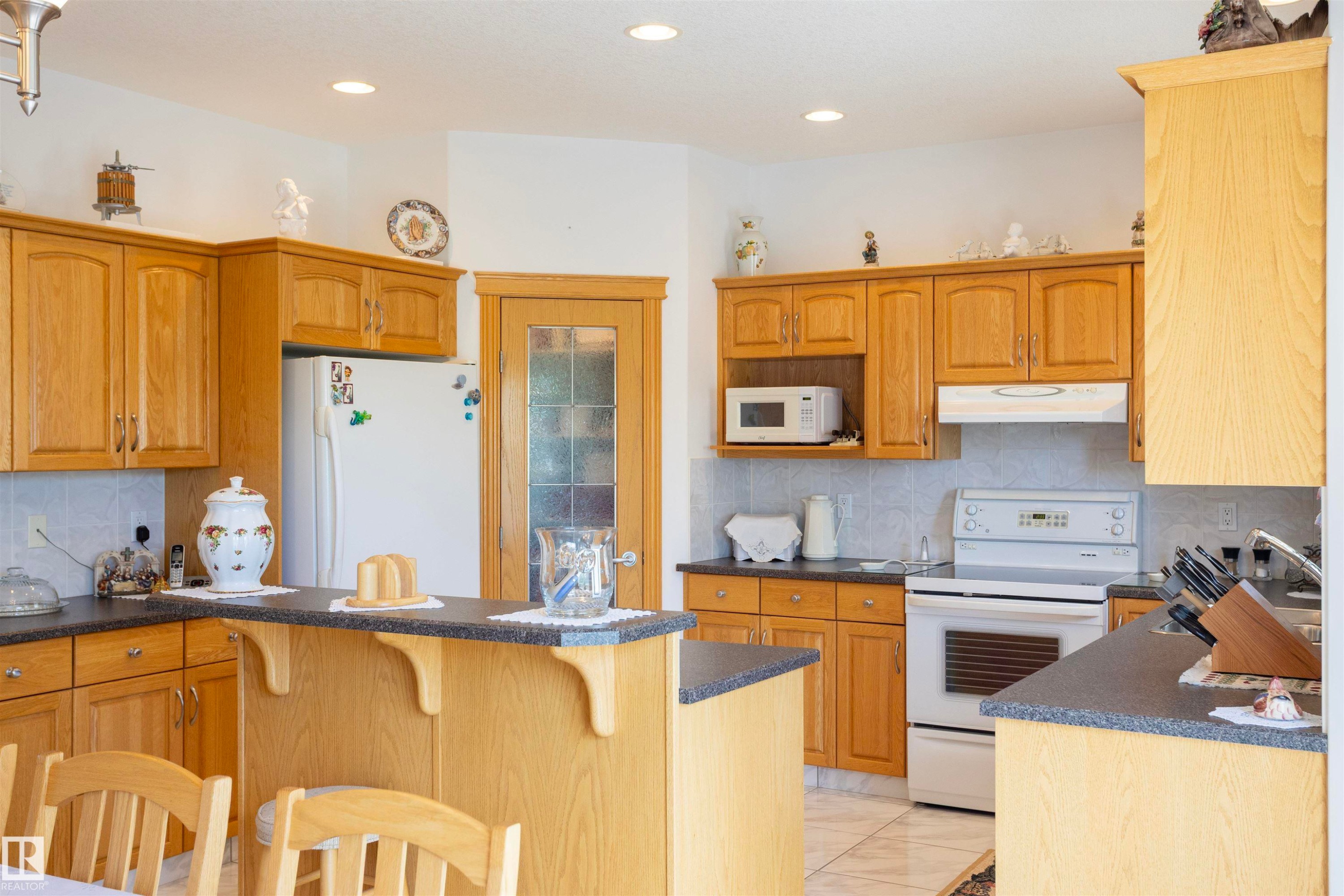 Kitchen featuring light wood cabinetry, stone-finish countertops, tile backsplash, and recessed lighting - 6407 163 Avenue Nw, Edmonton, AB