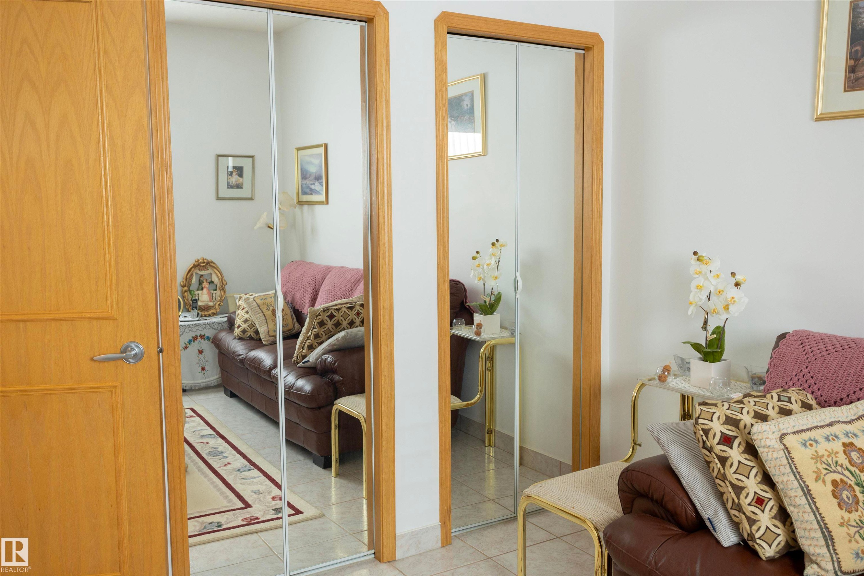 Light wood-paneled door with a brushed chrome handle, paired with a mirrored closet door featuring light wood trim - 6407 163 Avenue Nw, Edmonton, AB