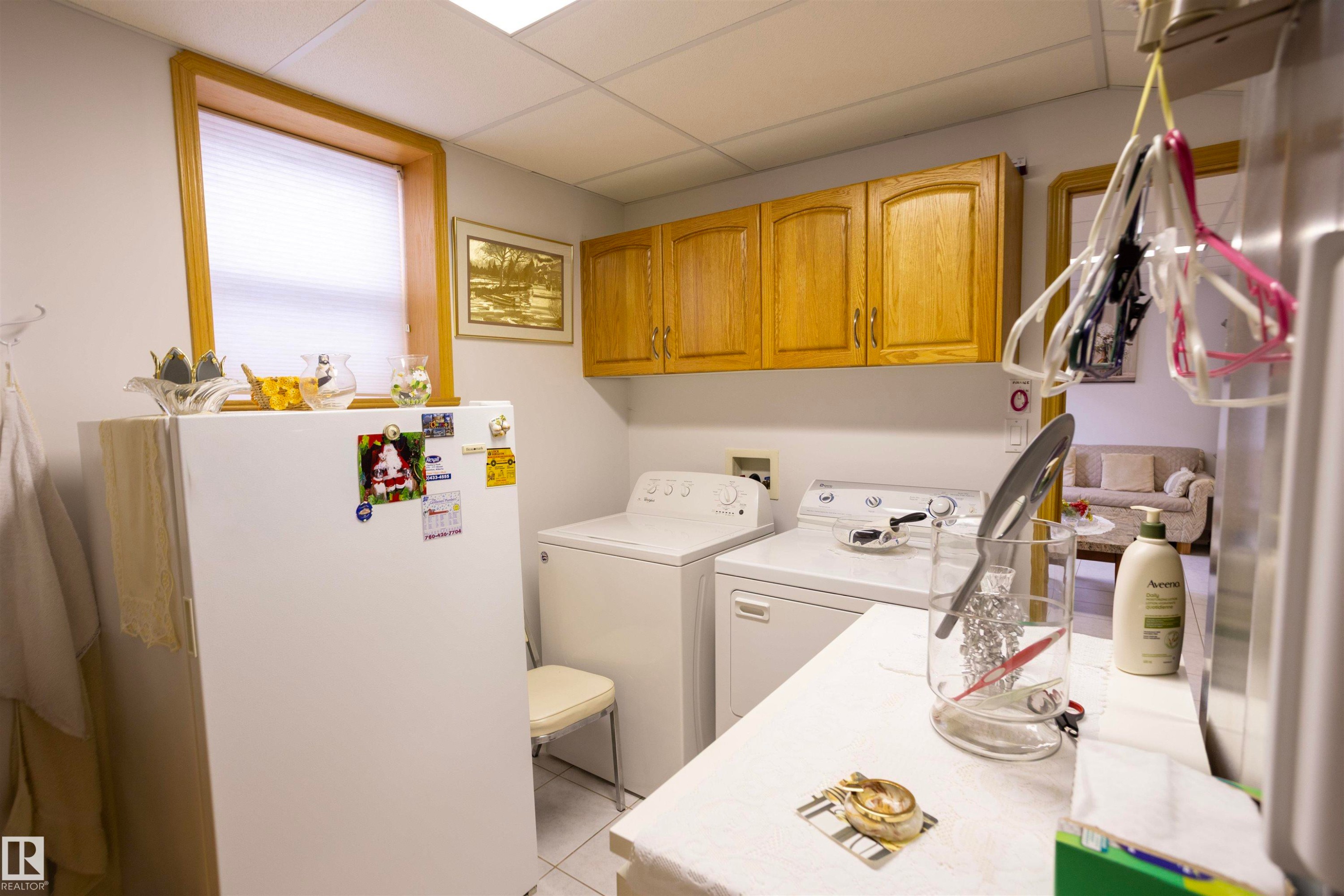 Utility space featuring a window, overhead cabinetry, and white tile flooring - 6407 163 Avenue Nw, Edmonton, AB