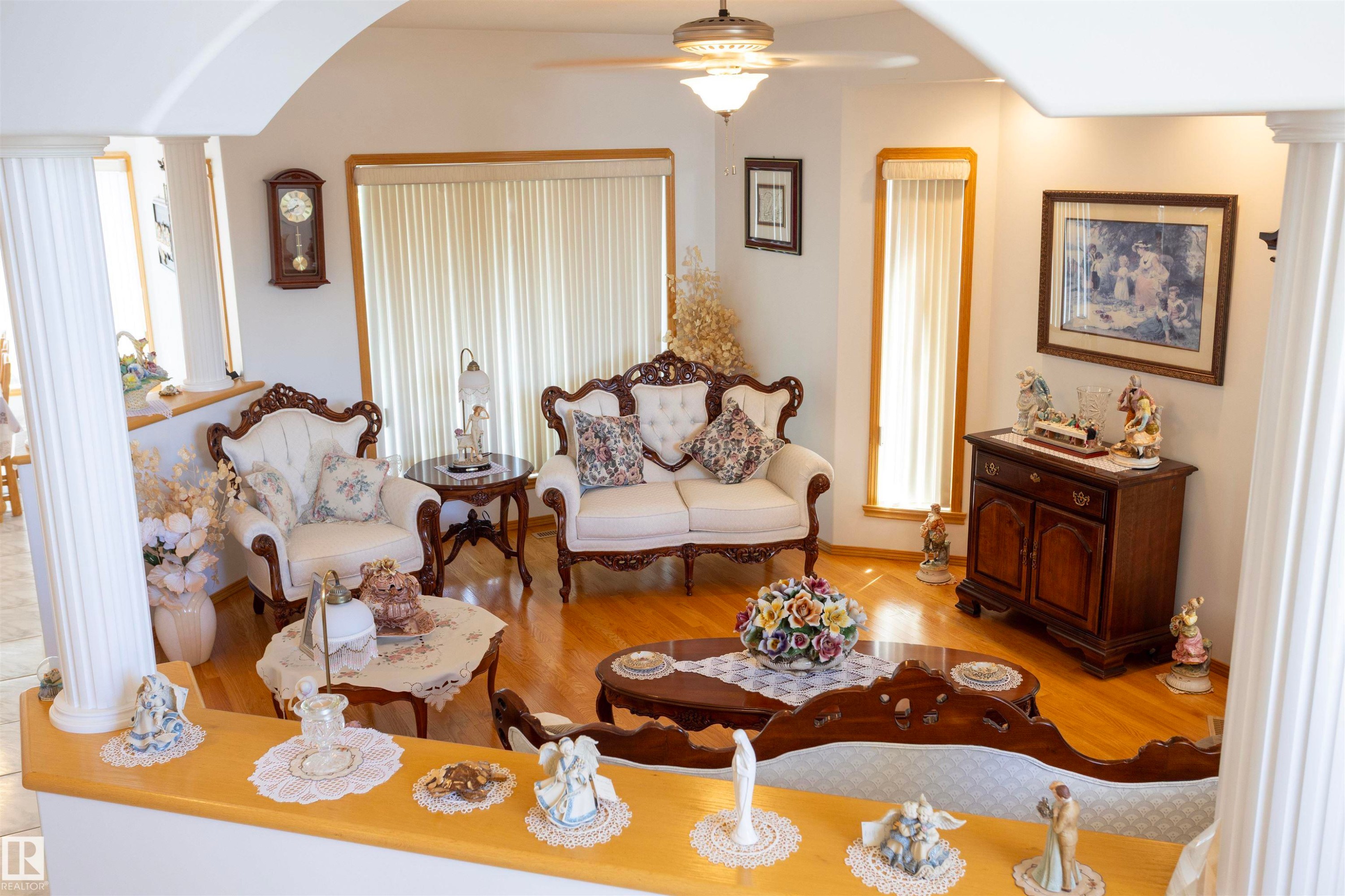 Spacious living area featuring light wood-finish flooring, white walls, and decorative architectural columns - 6407 163 Avenue Nw, Edmonton, AB