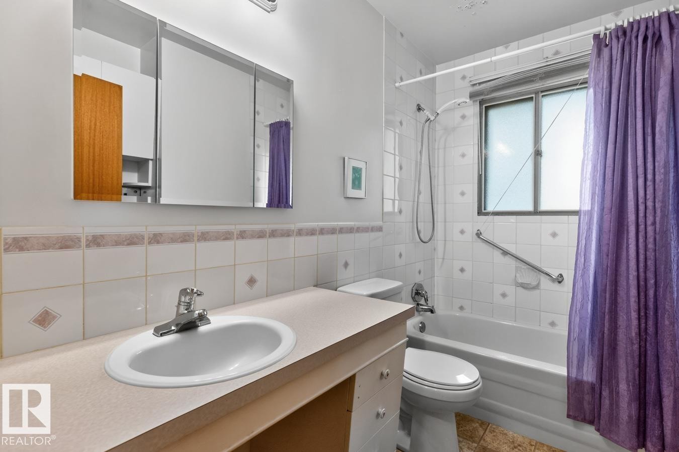 Vanity with integrated sink, three-panel mirrored medicine cabinet, tiled tub/shower combination, and window with privacy treatment - 12424 77 Street Nw, Edmonton, AB