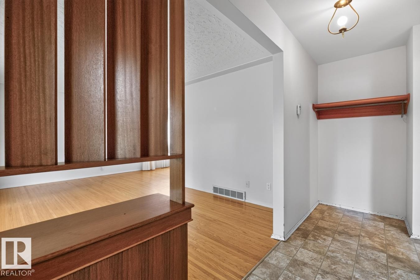 Wood slat room divider, light wood-finish flooring, recessed alcove with wood shelf, ceiling-mounted light fixture, tiled flooring - 12424 77 Street Nw, Edmonton, AB