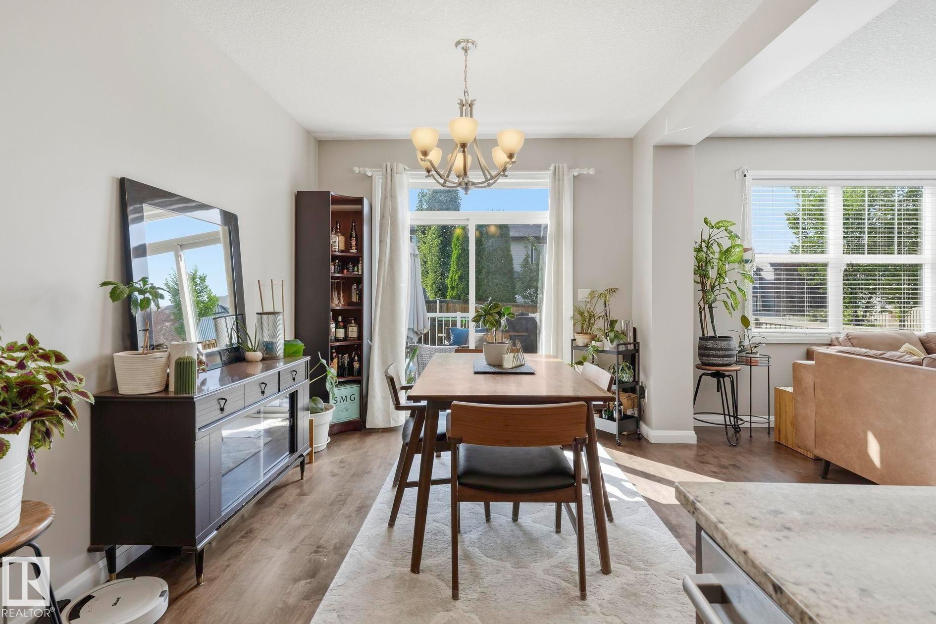 Dining area featuring wood-finish flooring, a contemporary chandelier, and a built-in storage cabinet - 3204 Abbott Crescent Sw, Edmonton, AB - Indoor Photo Showing Other Room