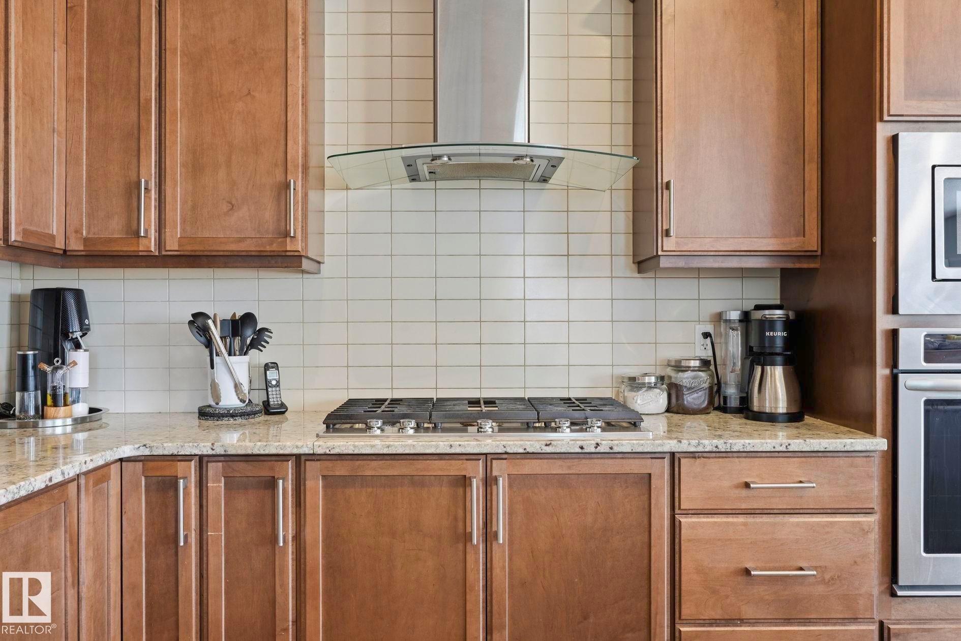 Modern kitchen featuring a gas range, stainless steel range hood, granite countertops, and light wood cabinetry - 3204 Abbott Crescent Sw, Edmonton, AB - Indoor Photo Showing Kitchen With Double Sink