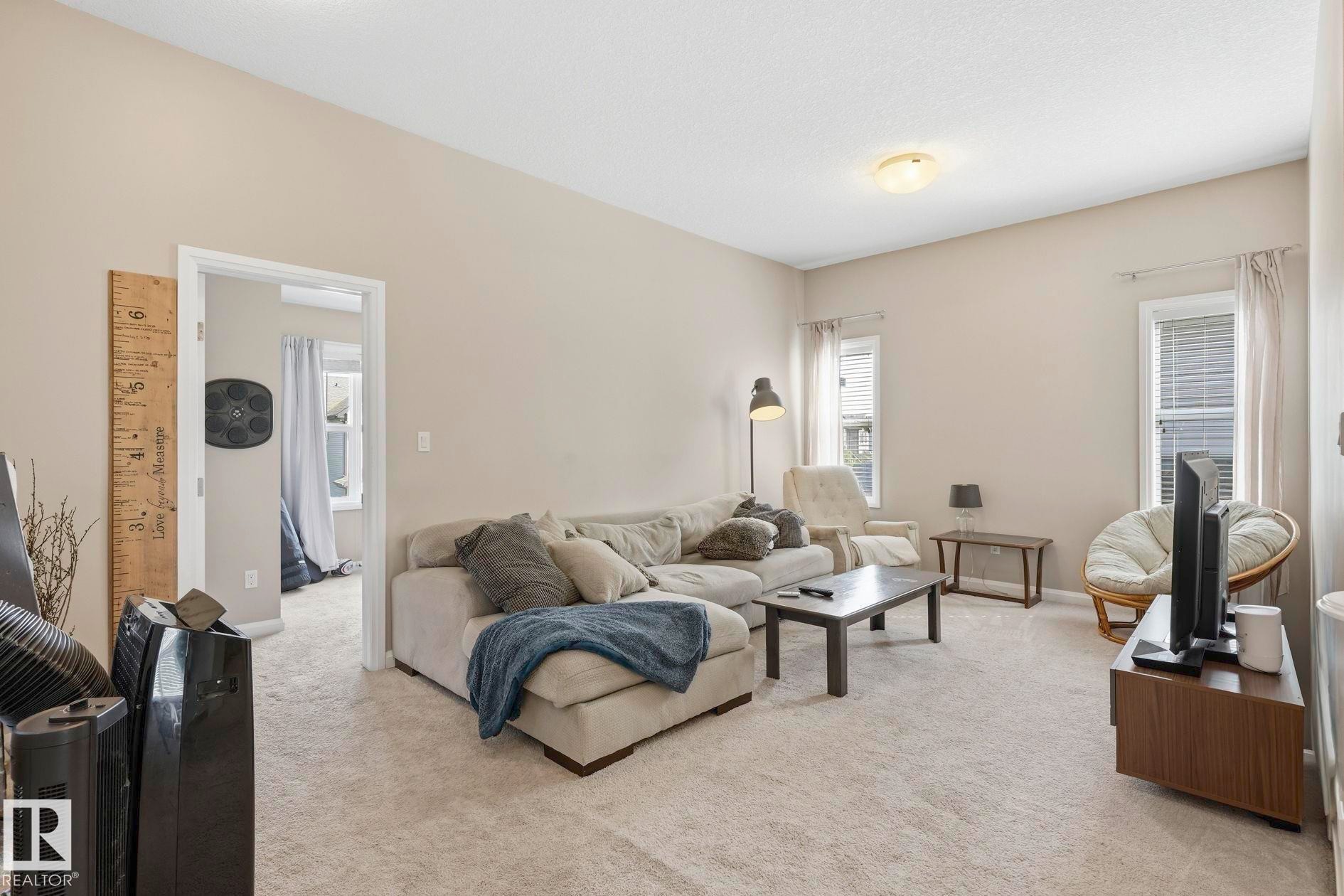 Living area featuring light beige walls and neutral carpeting - 3204 Abbott Crescent Sw, Edmonton, AB - Indoor