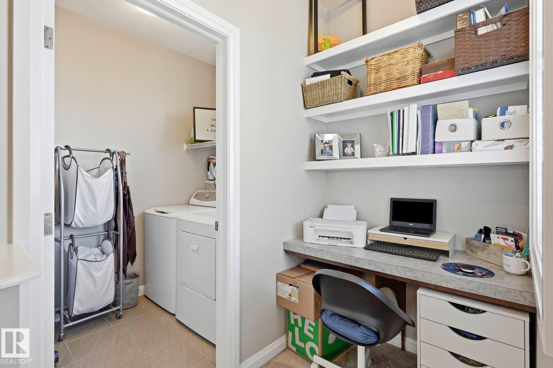Dedicated workspace featuring a built-in desk with a stone-finish countertop and three floating shelves - 3204 Abbott Crescent Sw, Edmonton, AB - Indoor Photo Showing Laundry Room