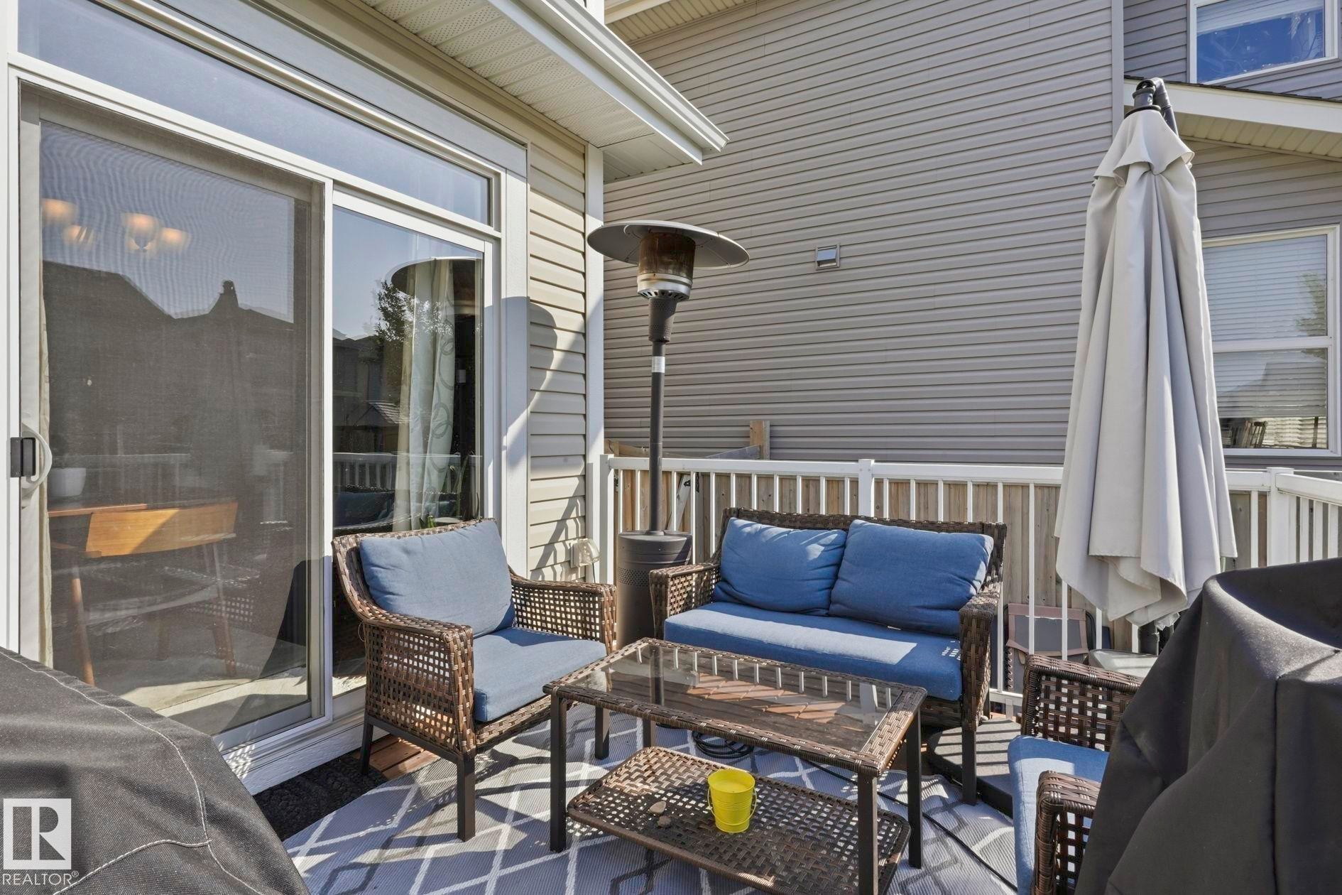 Exterior patio featuring a sliding glass door, overhead soffit, white railings, and siding - 3204 Abbott Crescent Sw, Edmonton, AB - Outdoor With Deck Patio Veranda With Exterior