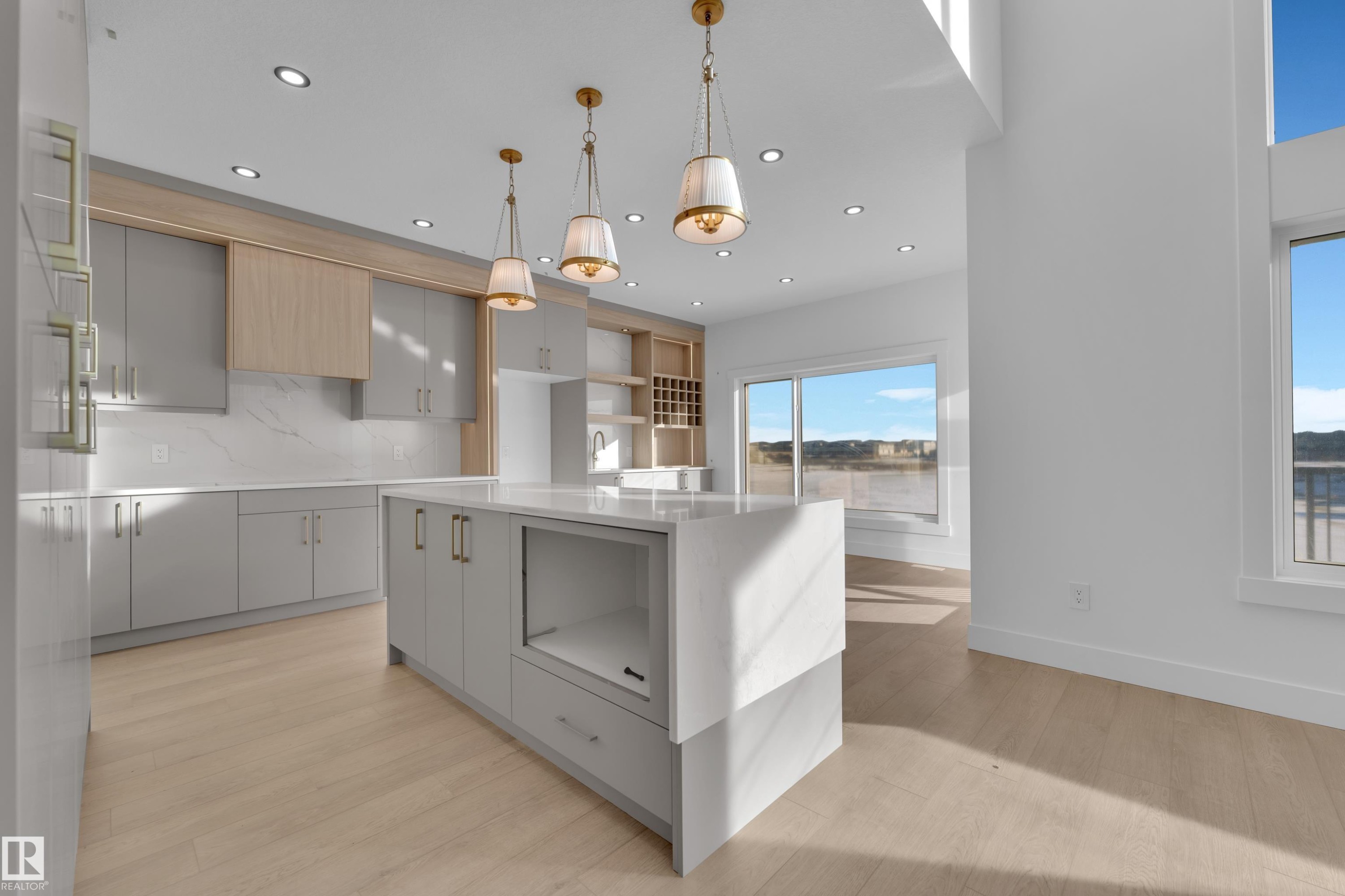 Kitchen featuring light wood-finish flooring, a large island with a waterfall countertop, recessed lighting, and pendant light fixtures - 226 Linden Loop, Leduc, AB
