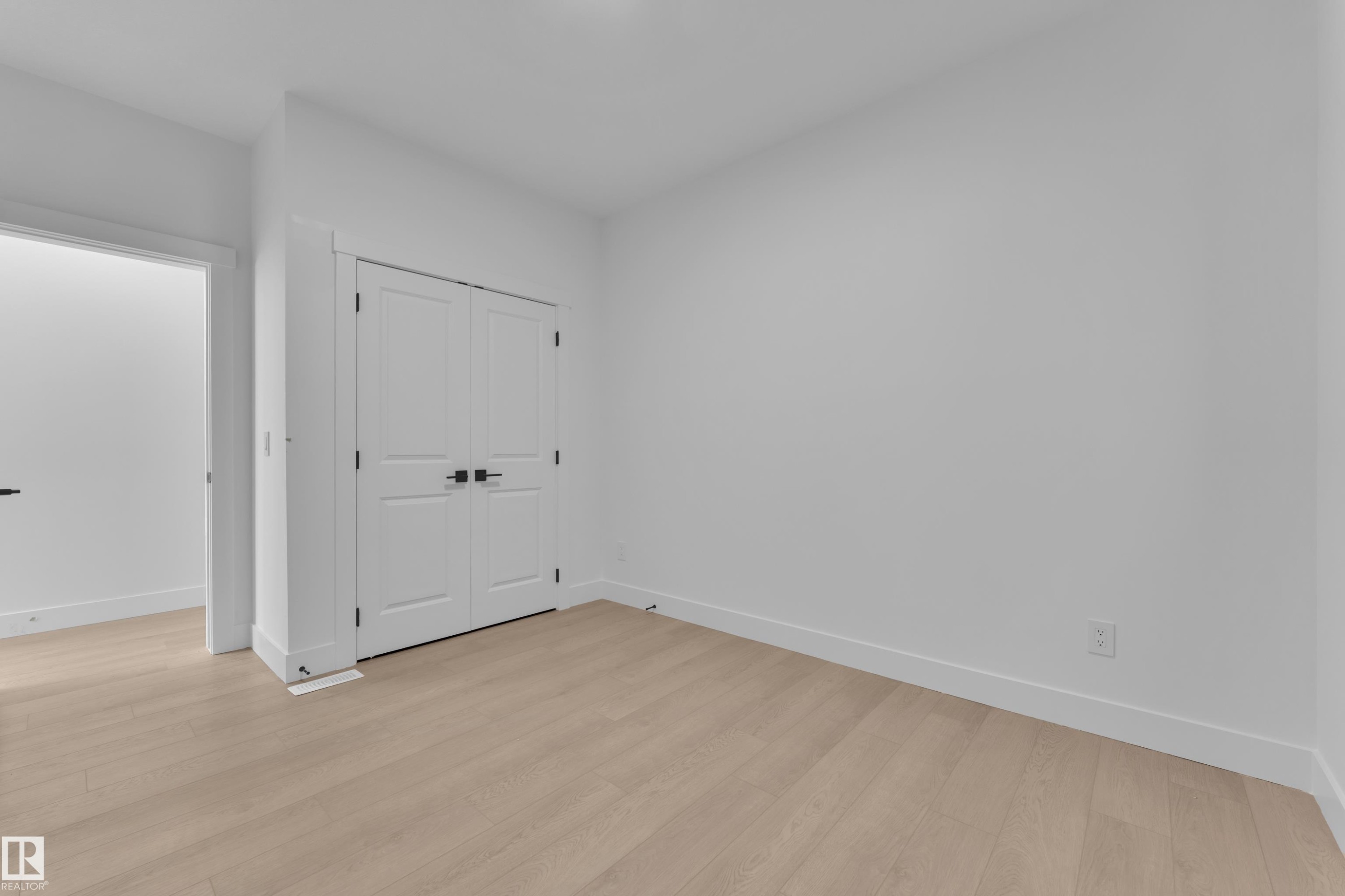 Light wood-finish flooring, white walls, and a double-door closet with black hardware - 226 Linden Loop, Leduc, AB