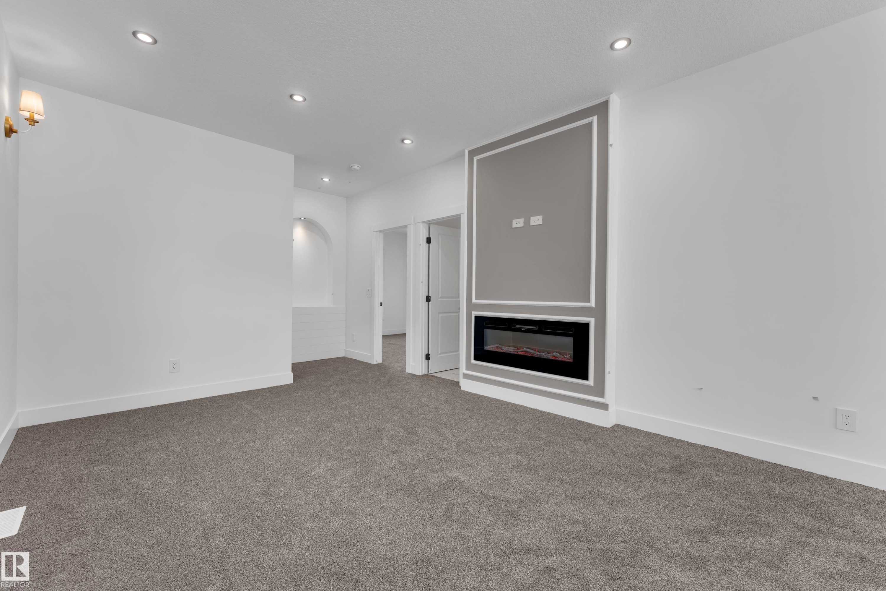 Recessed ceiling lighting, built-in electric fireplace with decorative molding, wall sconce, and carpeted flooring - 226 Linden Loop, Leduc, AB