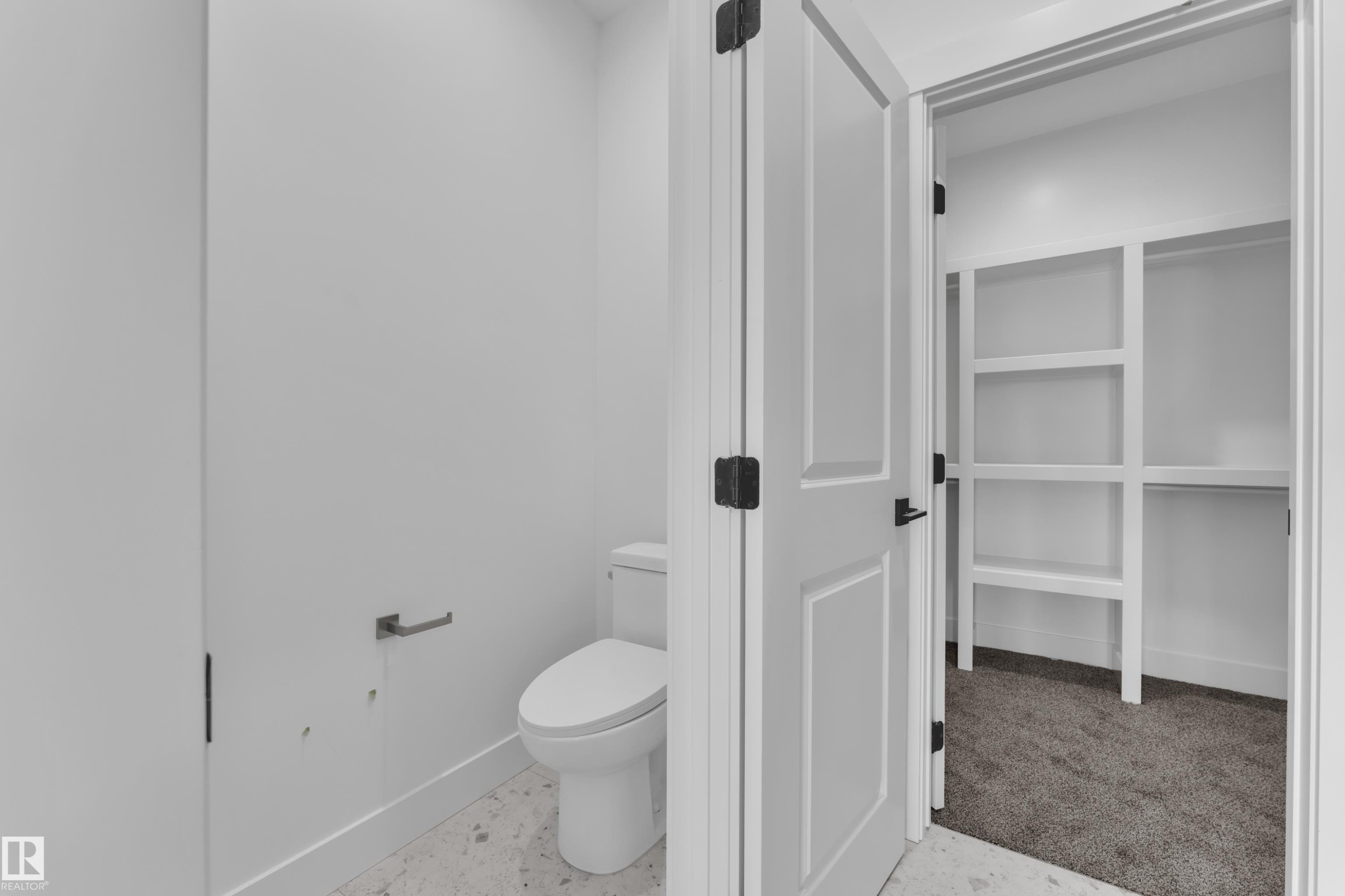White tile flooring, white commode, white interior doors, matte black door hardware, built-in shelving - 226 Linden Loop, Leduc, AB