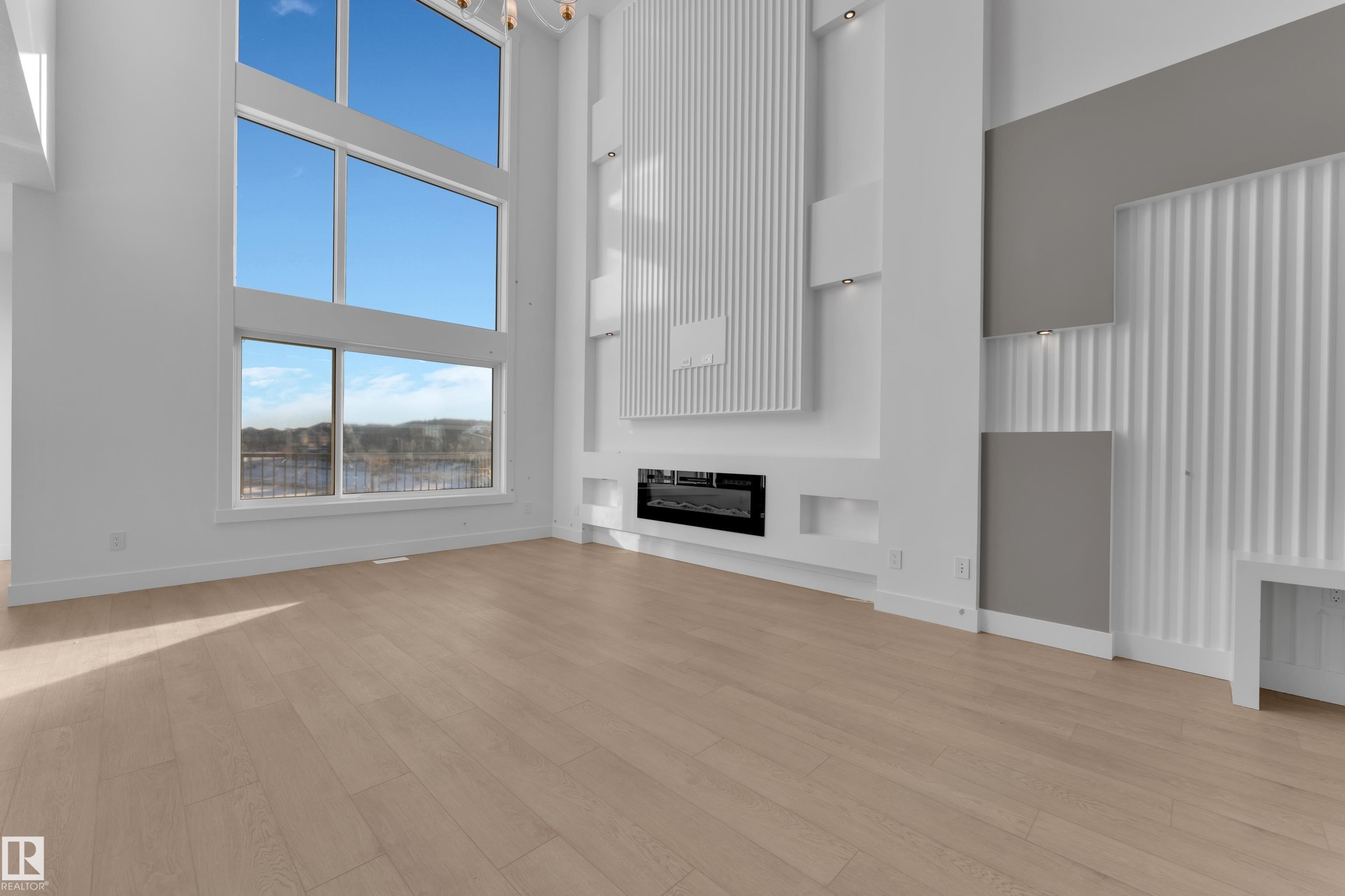 Tall windows, wood-finish flooring, built-in electric fireplace, recessed lighting, and decorative wall paneling - 226 Linden Loop, Leduc, AB