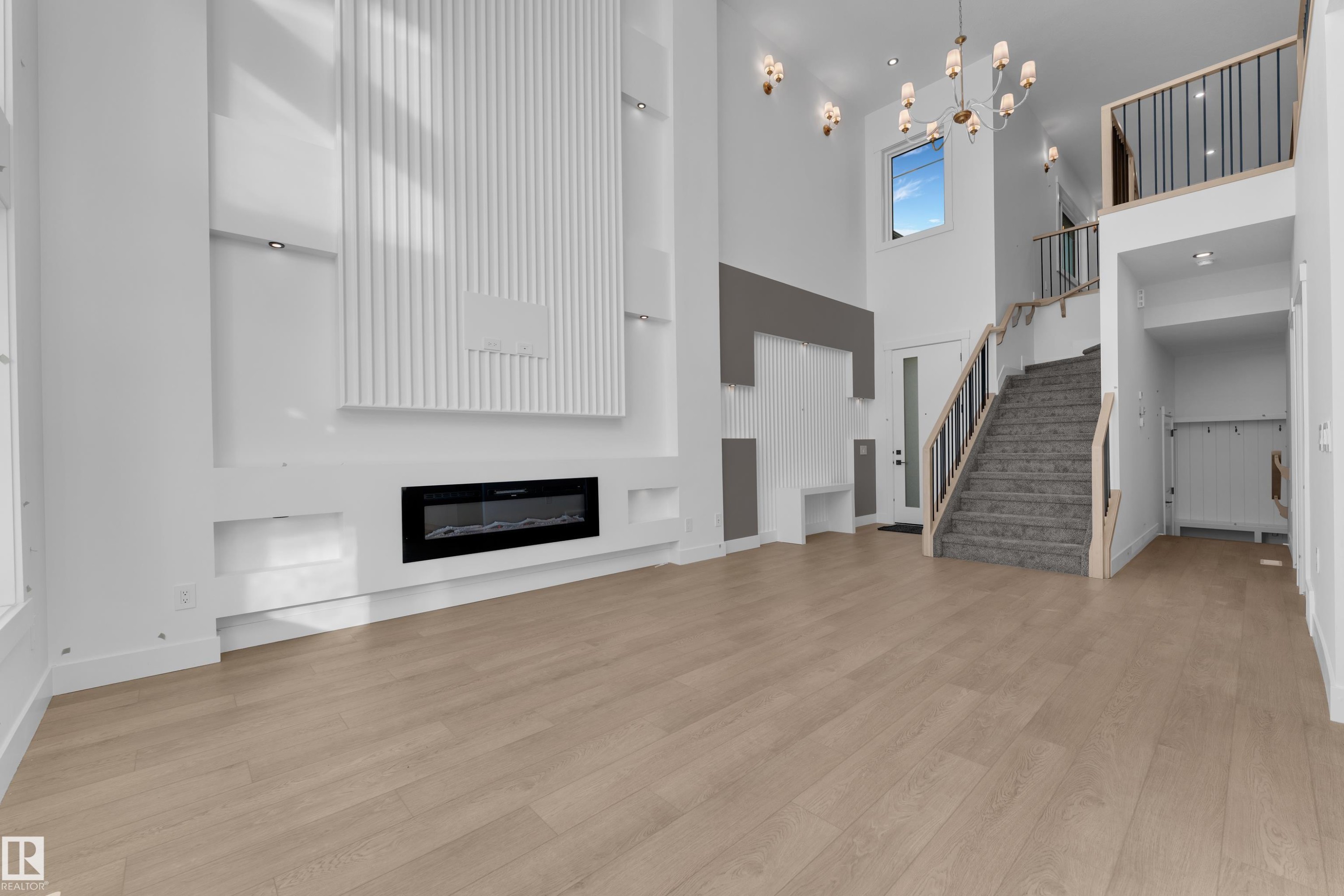 Two-story living area with wood-finish flooring and a fireplace feature wall - 226 Linden Loop, Leduc, AB
