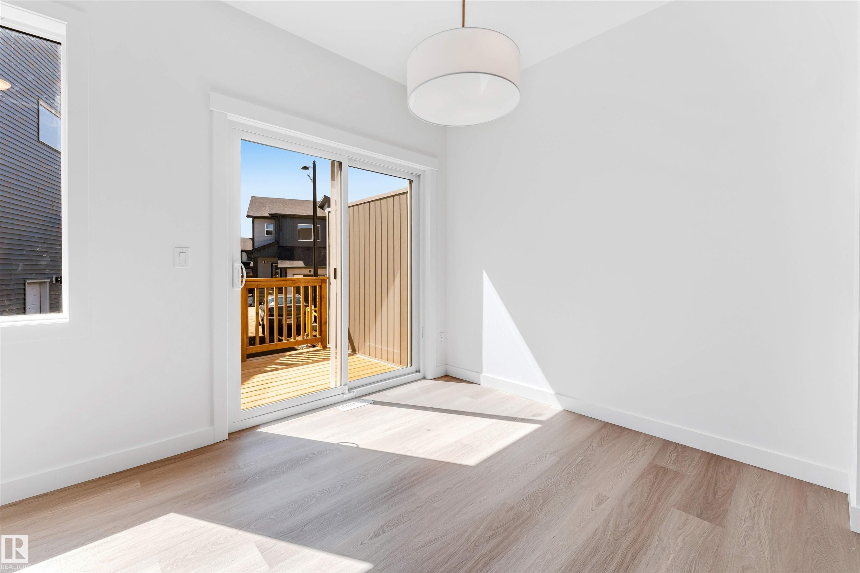 Wood-finish flooring, white walls, and a contemporary drum pendant light fixture - #48 710 Mattson Dr Sw Sw, Edmonton, AB