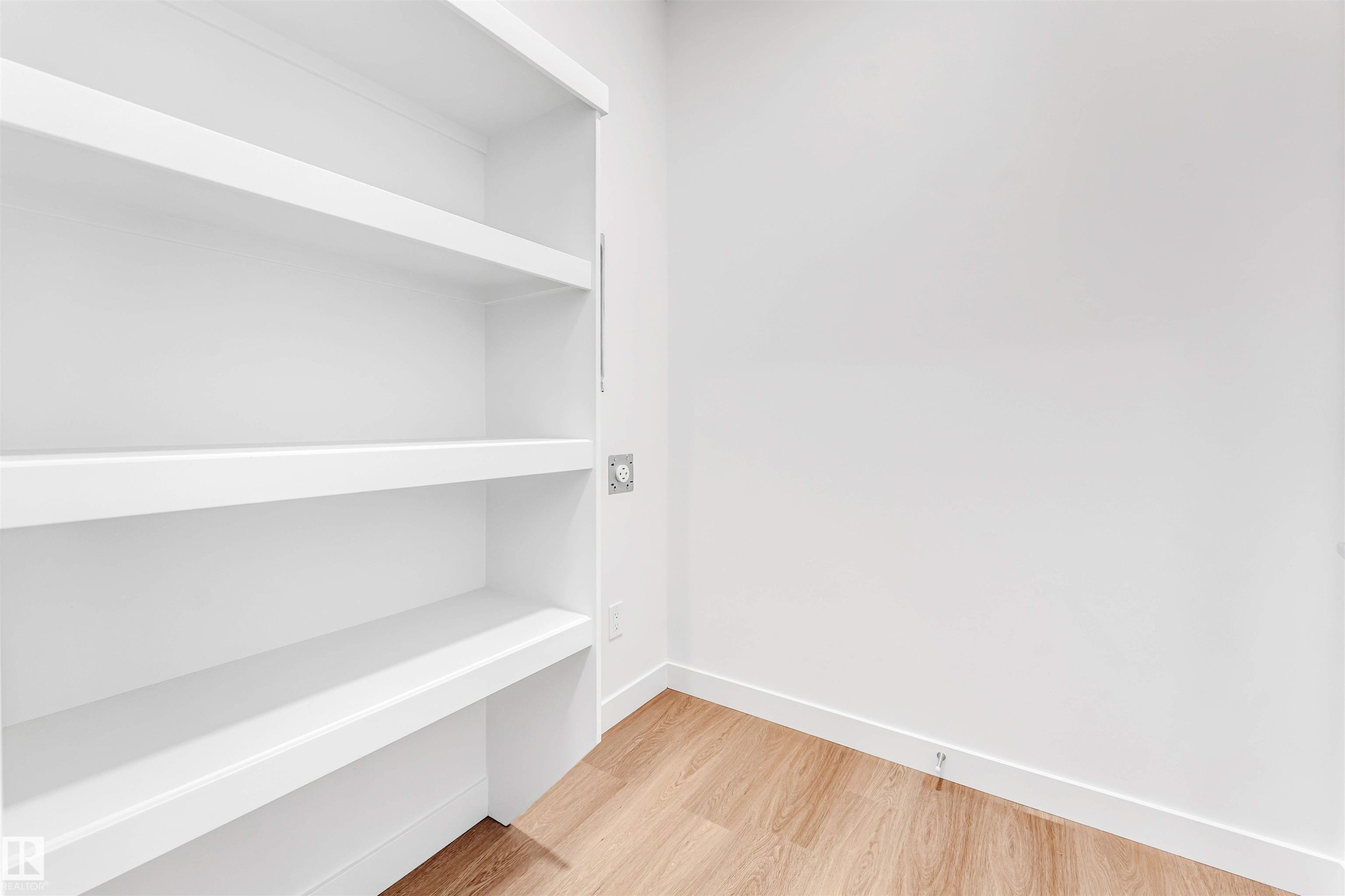 Built-in shelving unit with white finish, integrated power outlet, and wood-finish flooring - #48 710 Mattson Dr Sw Sw, Edmonton, AB